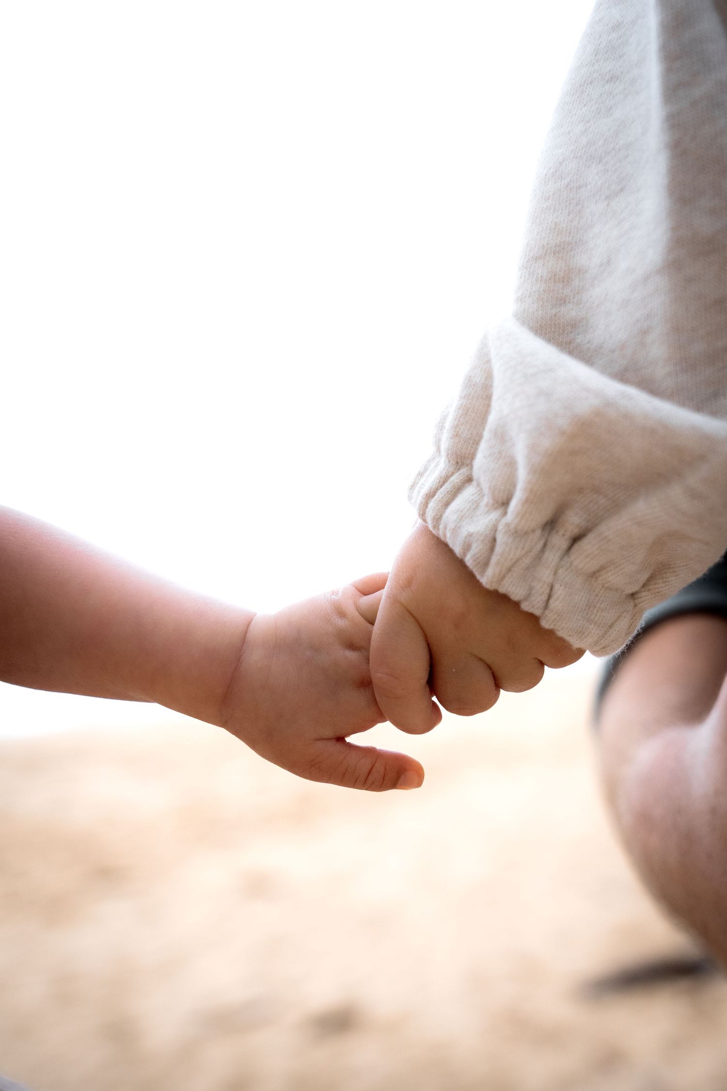 Tiny baby hand grasping adult finger in a heartwarming close-up parenting moment.