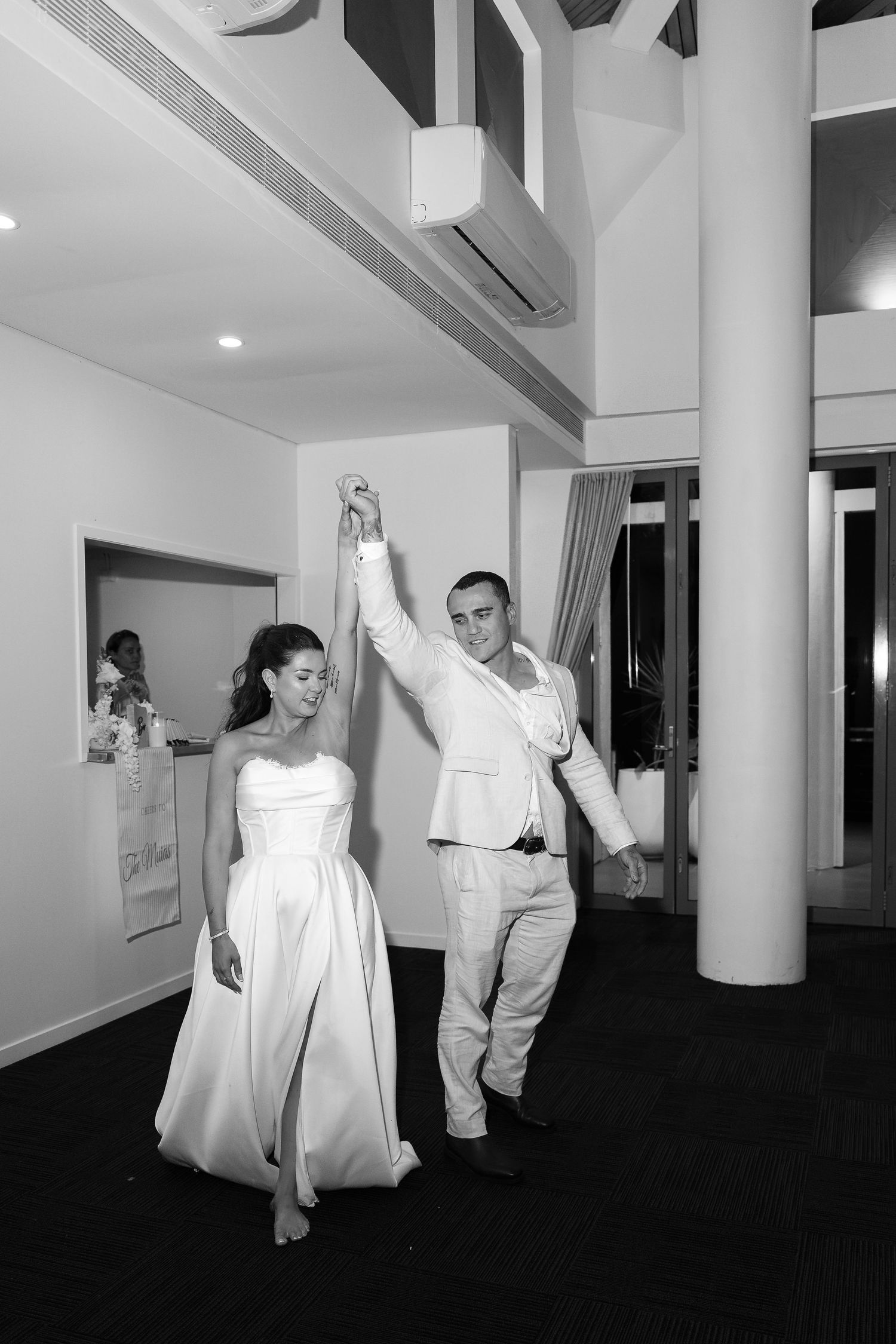 Black and white photo of a bride and groom dancing together at their wedding reception in an elegant venue.