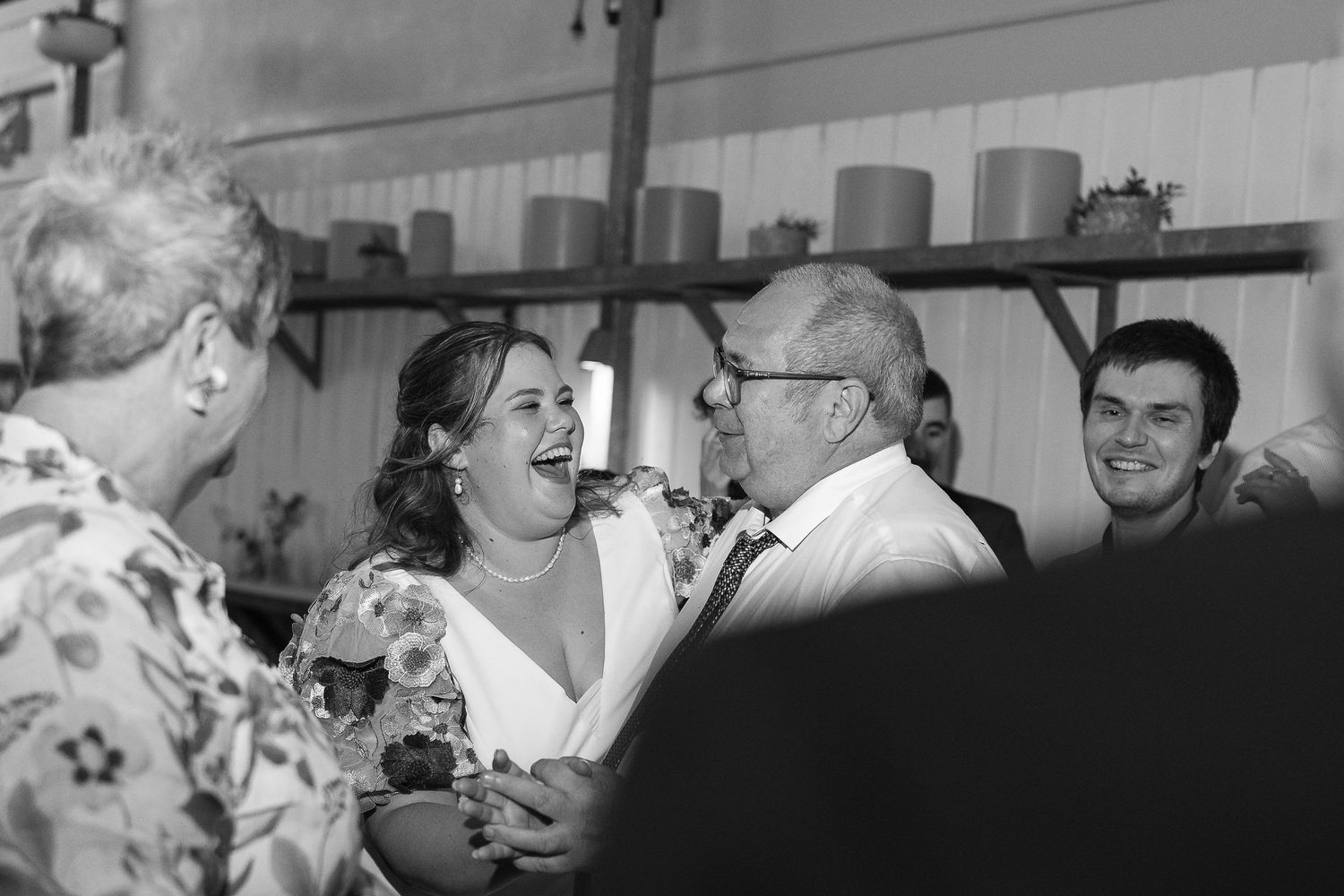 Black and white photo of a bride laughing joyfully with an older man at a wedding reception.