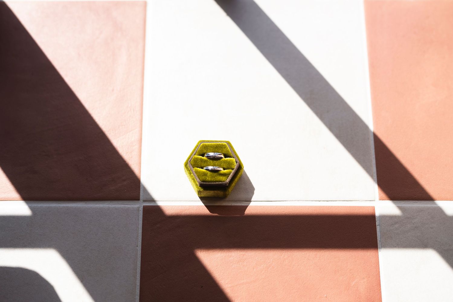 Yellow hexagonal decorative object on colorful tiled surface with geometric shadows in pink and white.