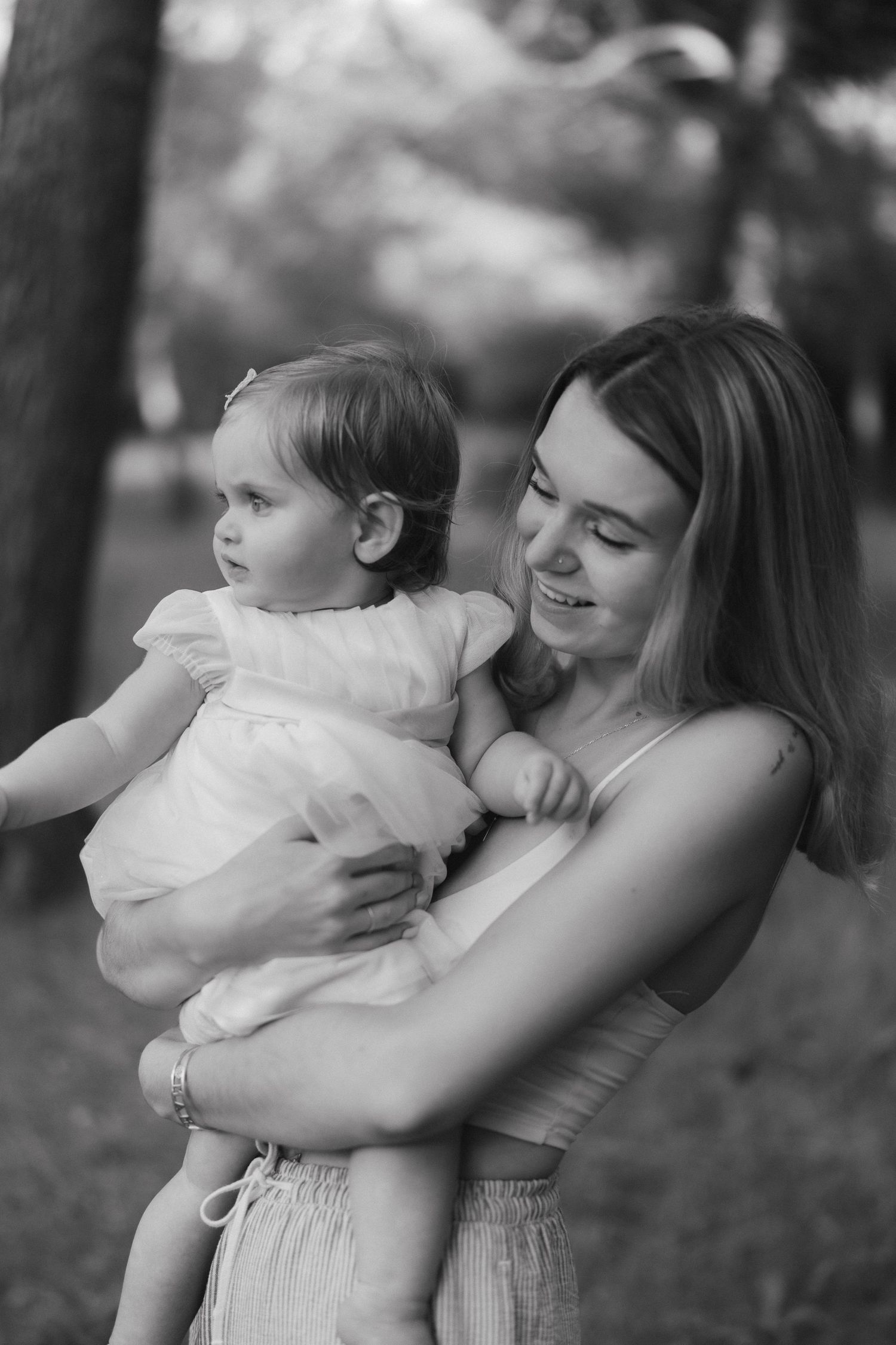 A tender moment captured in black and white as a mother and baby share joyful embraces outdoors.