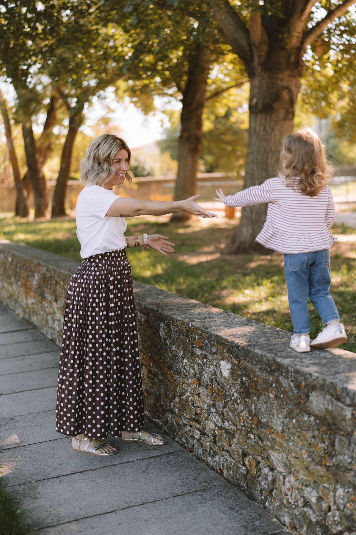 A series of candid shots showing playful interaction on a stone wall in a sunlit park setting.
