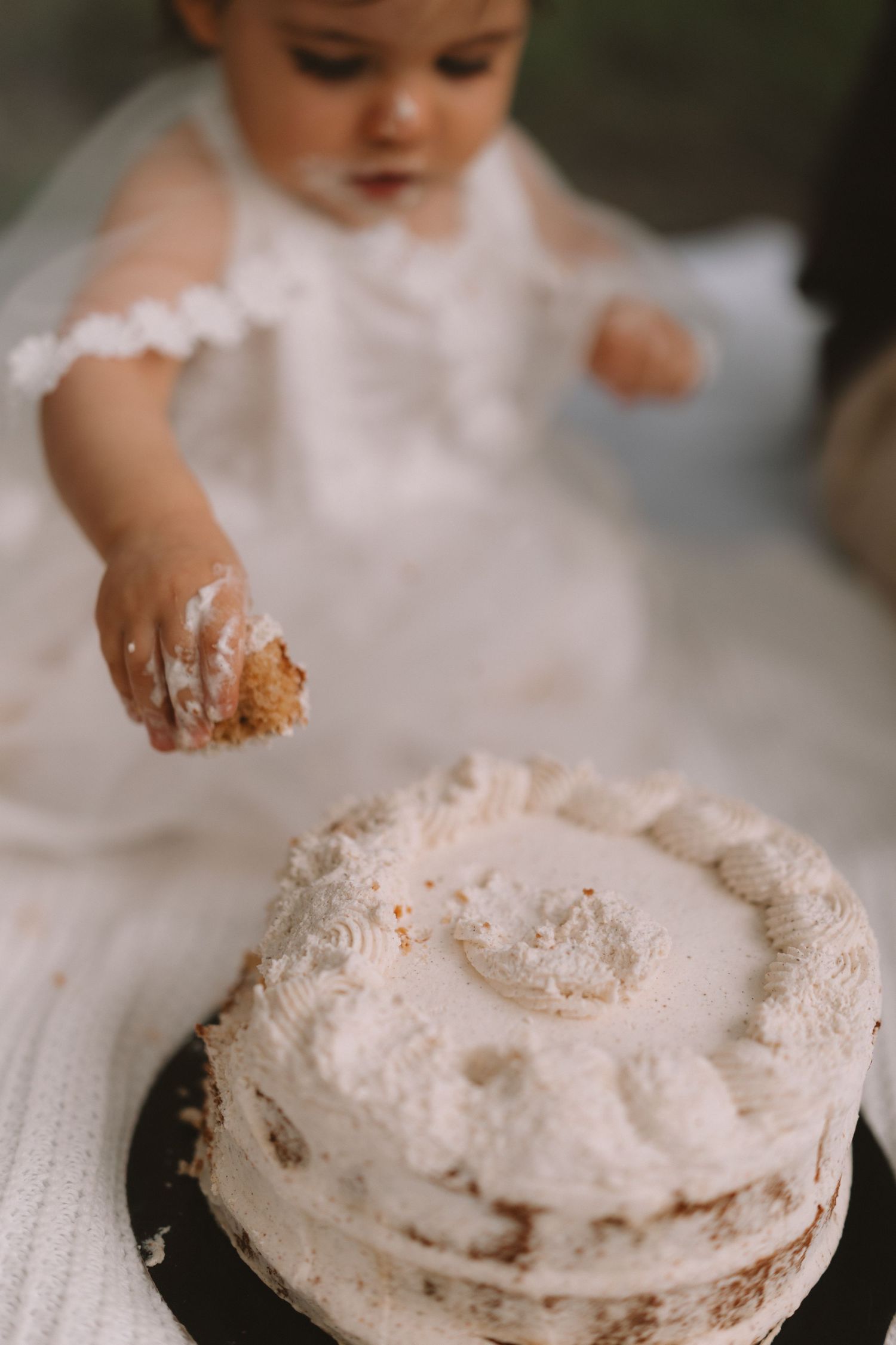 A sequence of photos showing a small hand smashing into a white frosted cake during a cake smash photo session.