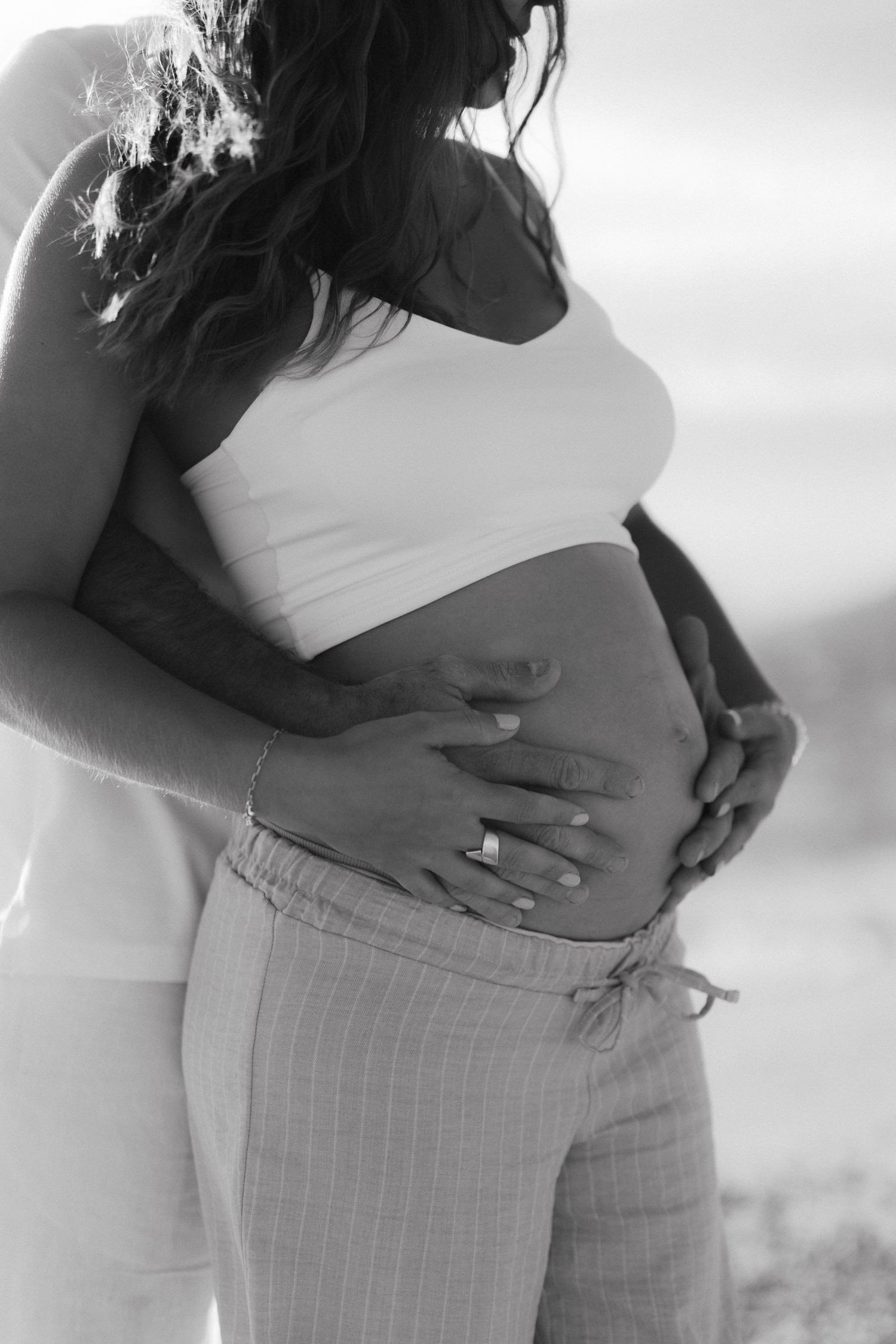 Black and white maternity photo series showing pregnant belly in profile against soft background.