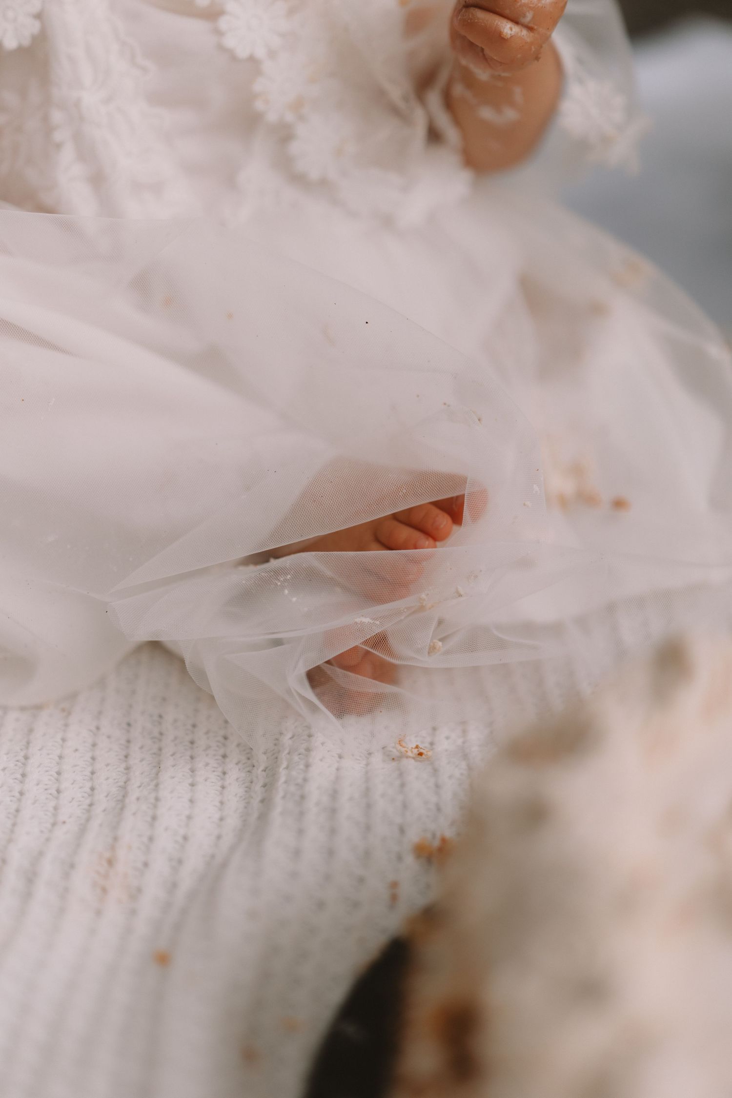 Close-up detail of delicate white tulle fabric layered over a knitted sweater texture.