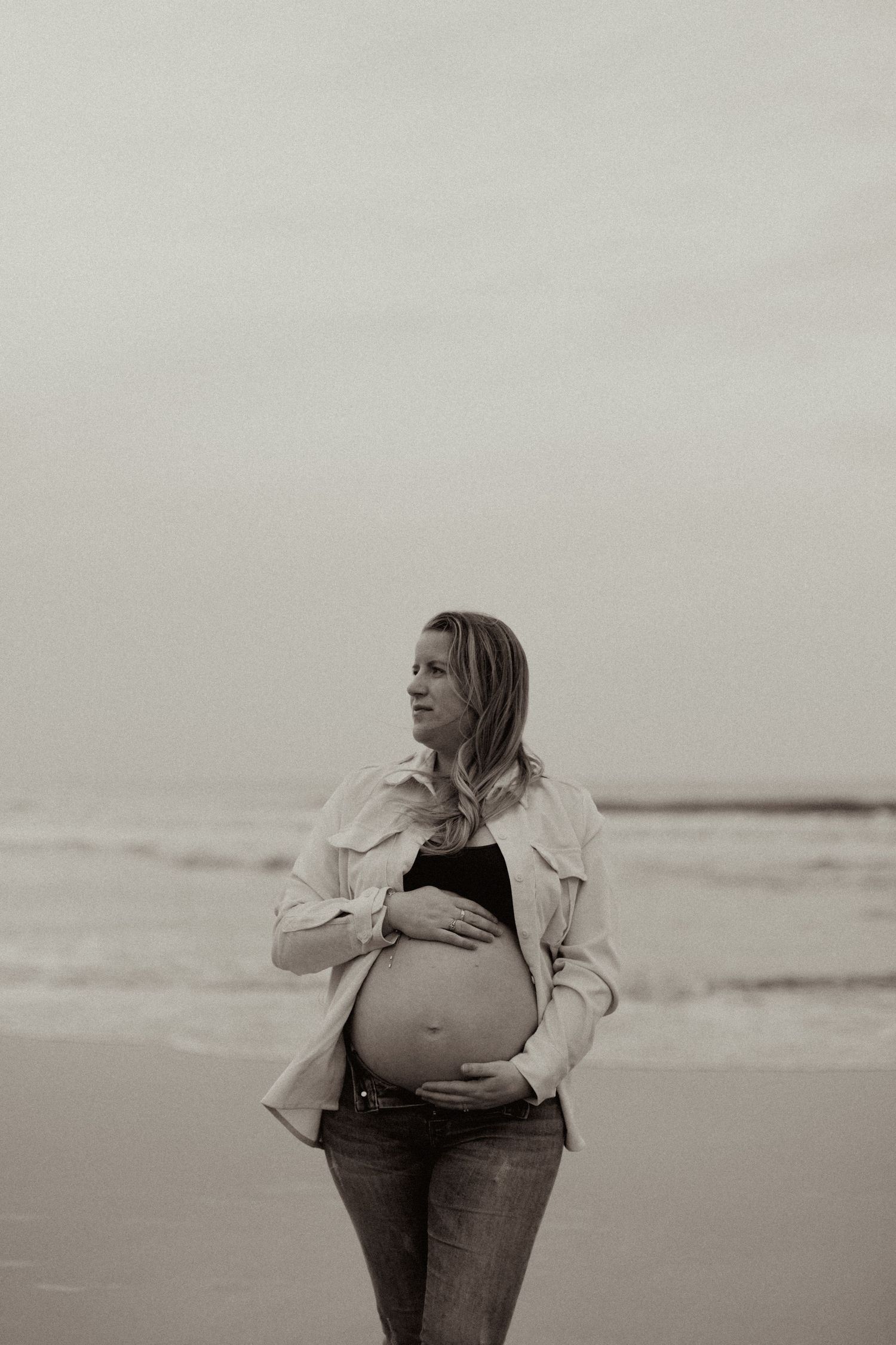 Mooie zwangere vrouw op het strand met de wind in haar haren