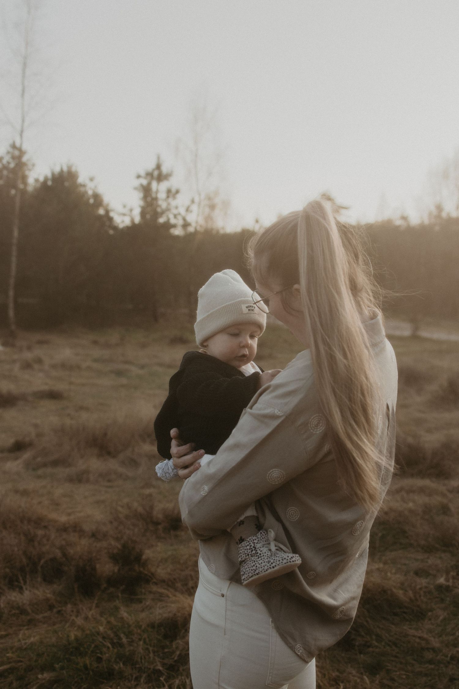 Kindje van 1 jaar die gedragen wordt door haar moeder.