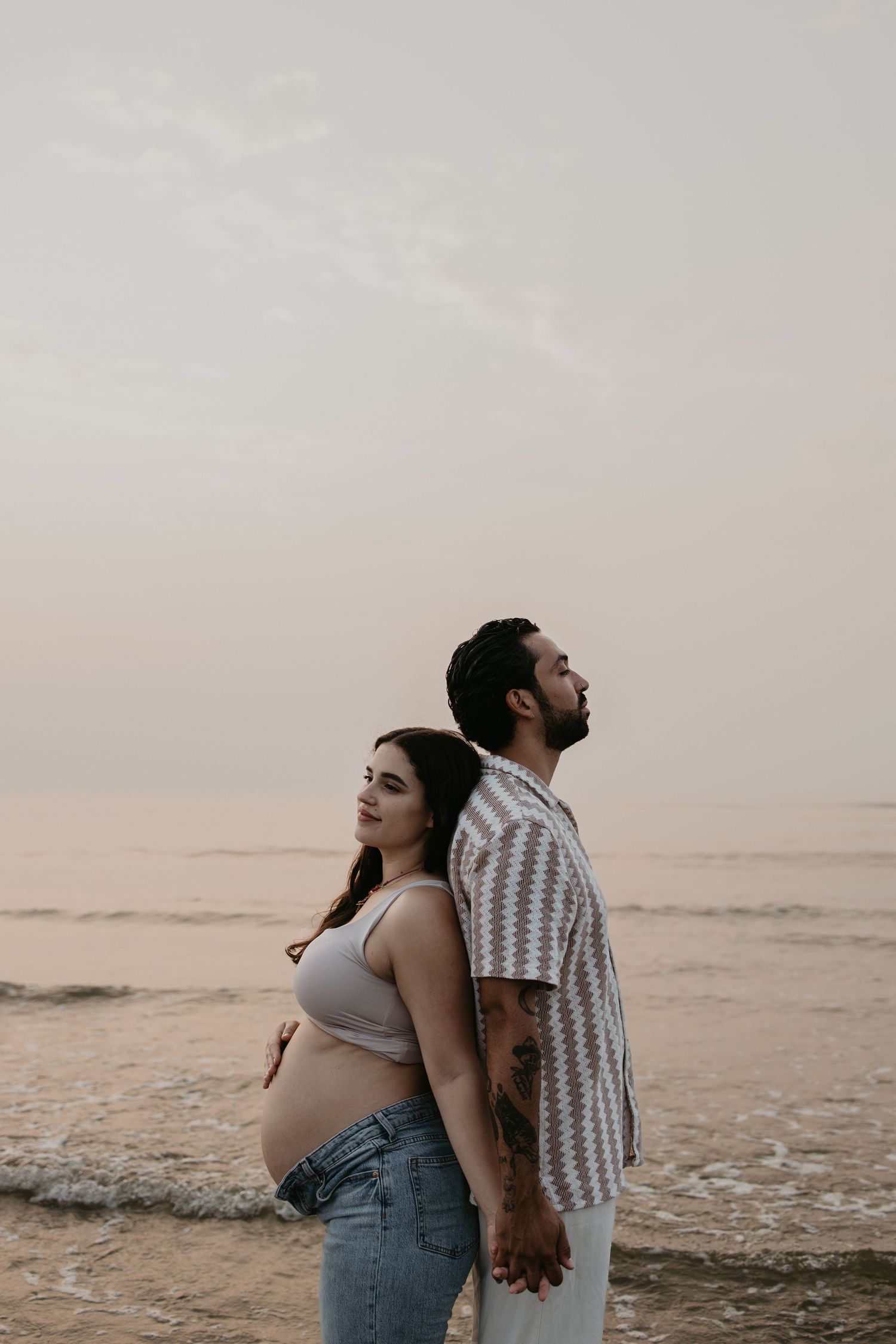 Een zwangere vrouw samen met haar partner bij de zee