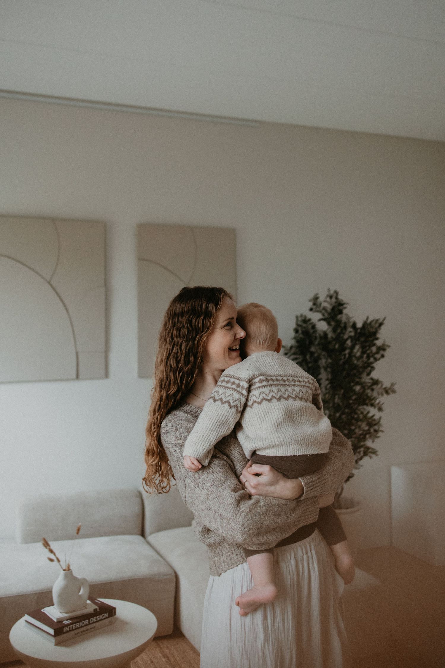 Moeder geniet van een zacht moment met haar kind in een warme, comfortabele woonomgeving.
