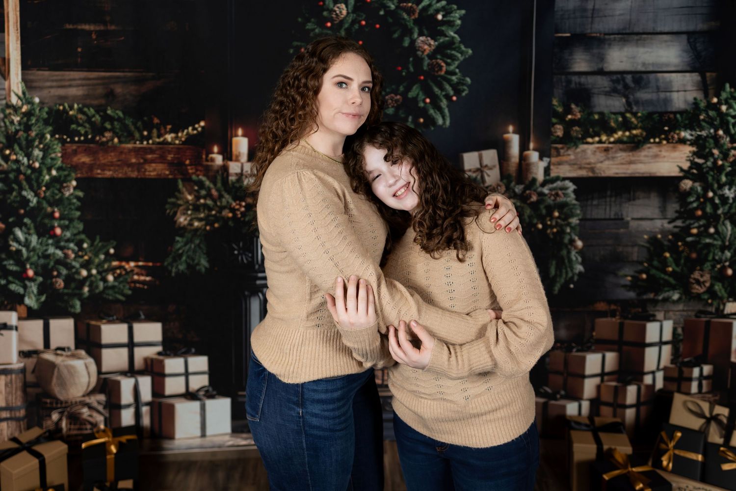 Two people in matching beige sweaters pose together for a holiday portrait.