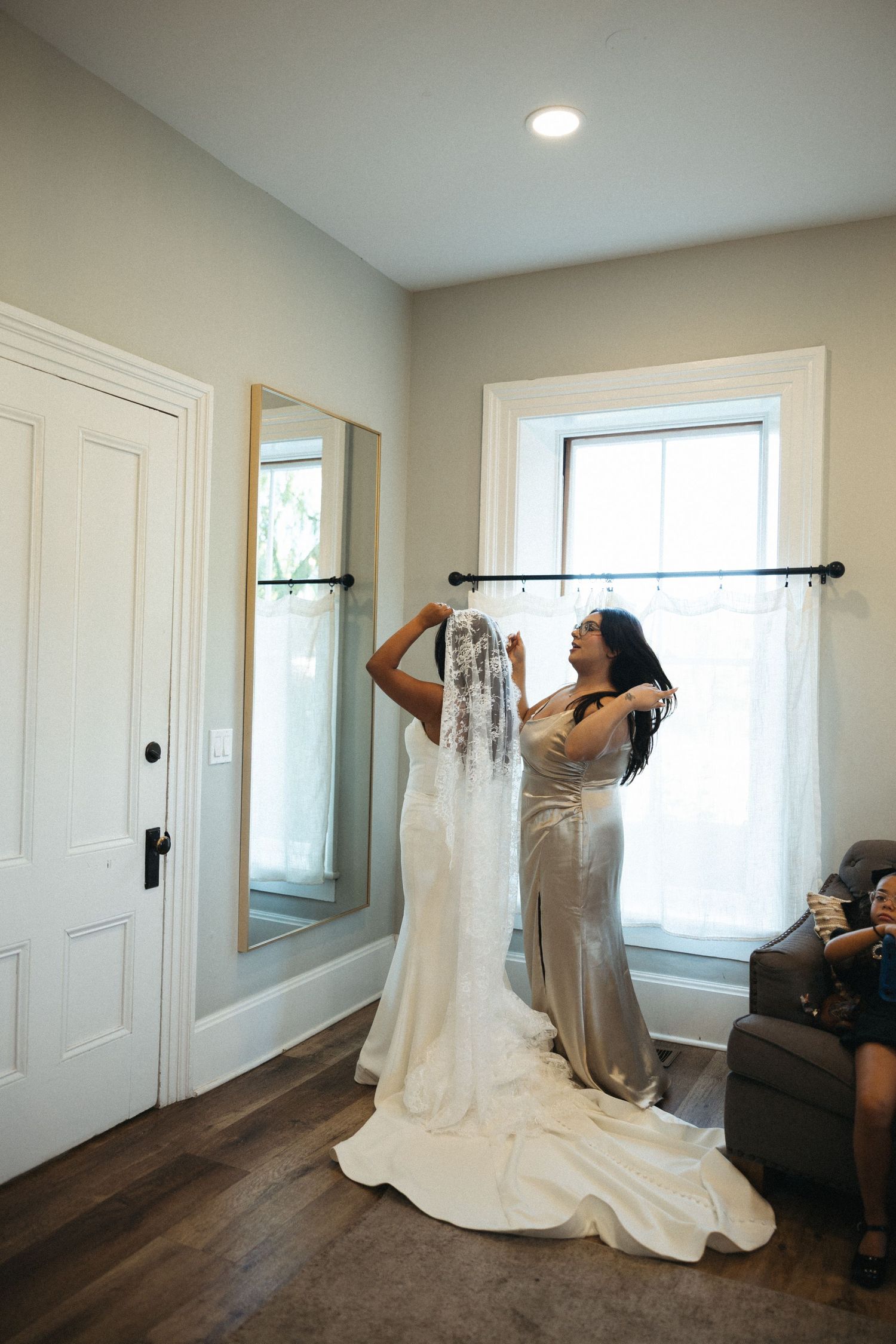 A series of photos showing someone putting on a white wedding dress in a bright, modern room with hardwood floors.