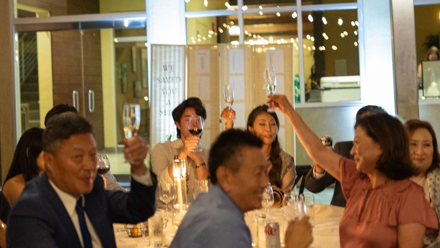 A group of people raising glasses for a toast at an elegant dinner gathering. Documentary/ photojournalist photography