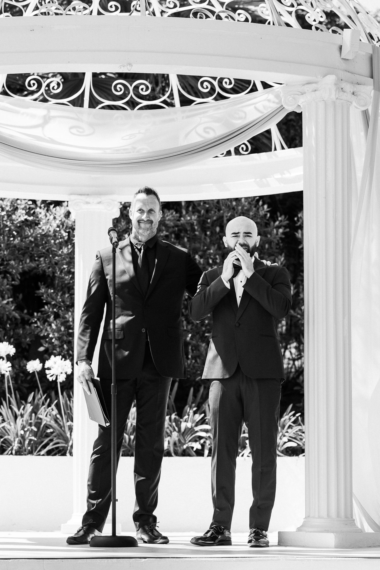 Black and white photo series showing three groomsmen in formal suits posing together at an outdoor wedding venue. Micro wedding, intentional