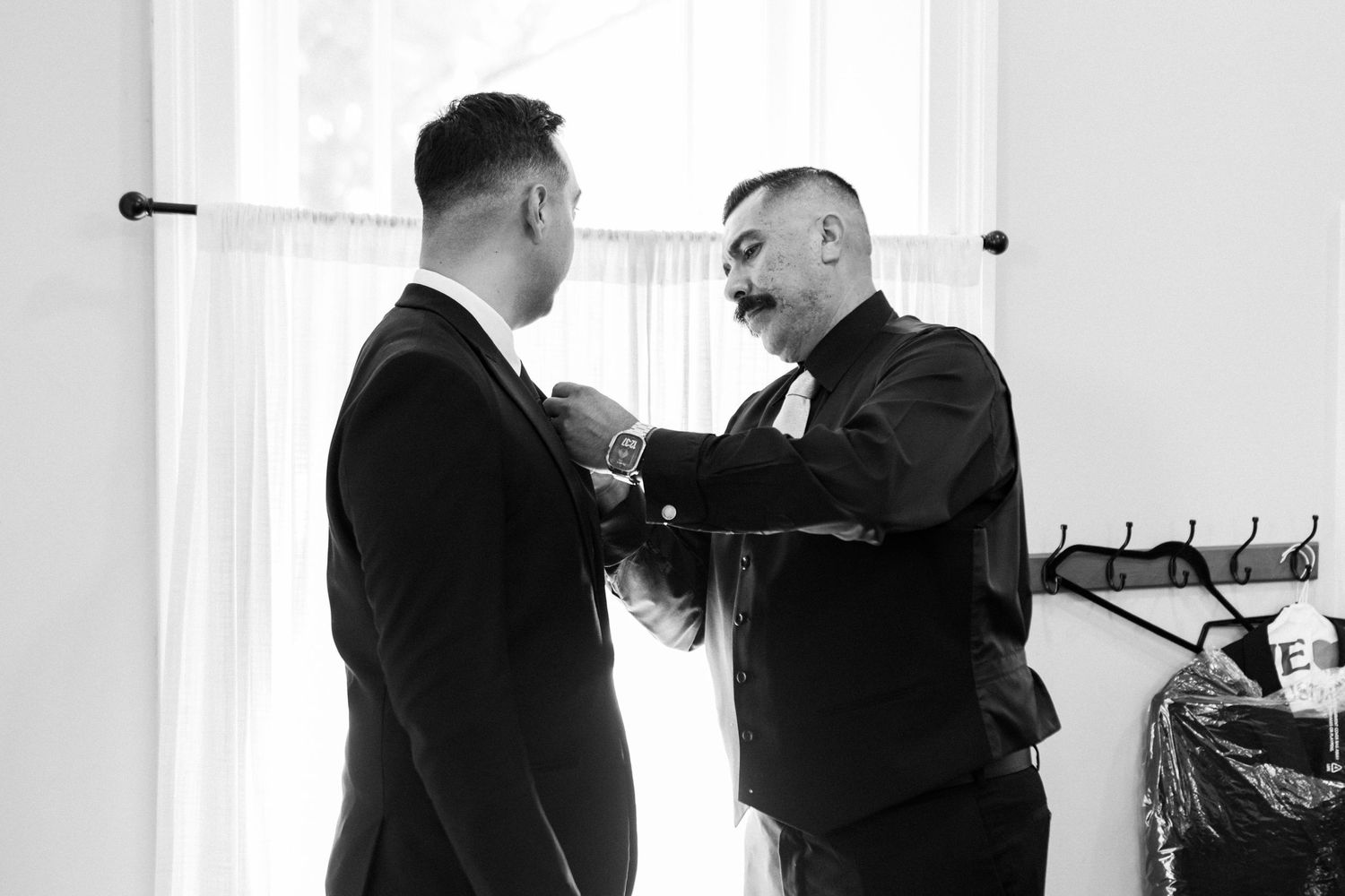 Two people in formal attire adjusting neckties and preparing for a formal event.
