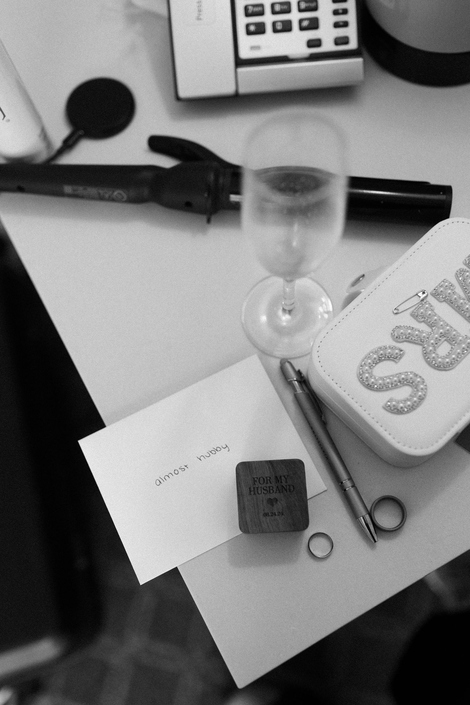 A black and white overhead shot of a desk with office supplies, notes, and a wine glass. Documentary/ photojournalist photography