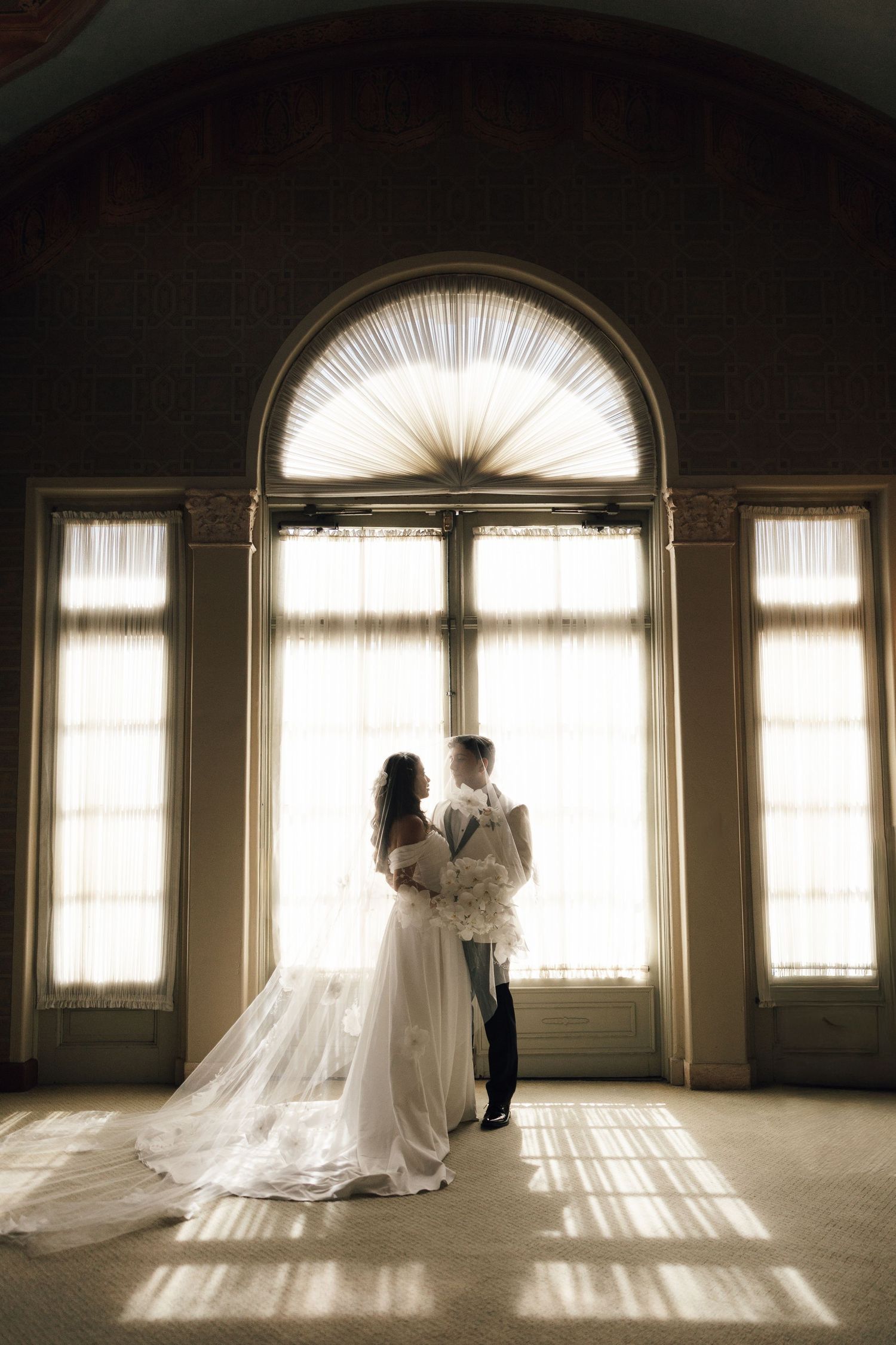 A series of sepia-toned photos showing silhouettes against sunlit windows in an elegant room with long flowing wedding dress.