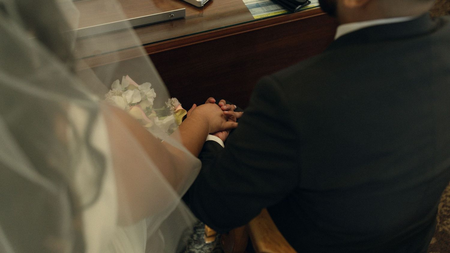 A person's hands carefully wrapping a gift with brown paper and twine on a wooden surface. Micro wedding, intentional celebrations