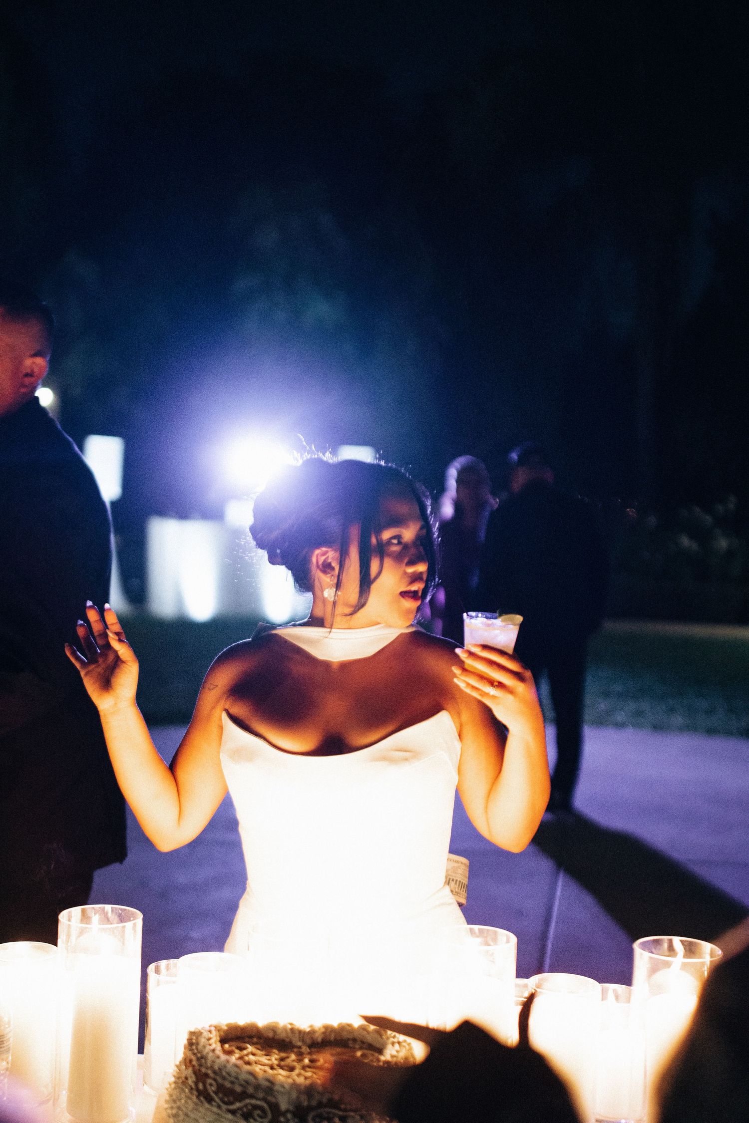 A silhouetted figure illuminated by candlelight holds up their hands in a dramatic nighttime scene.