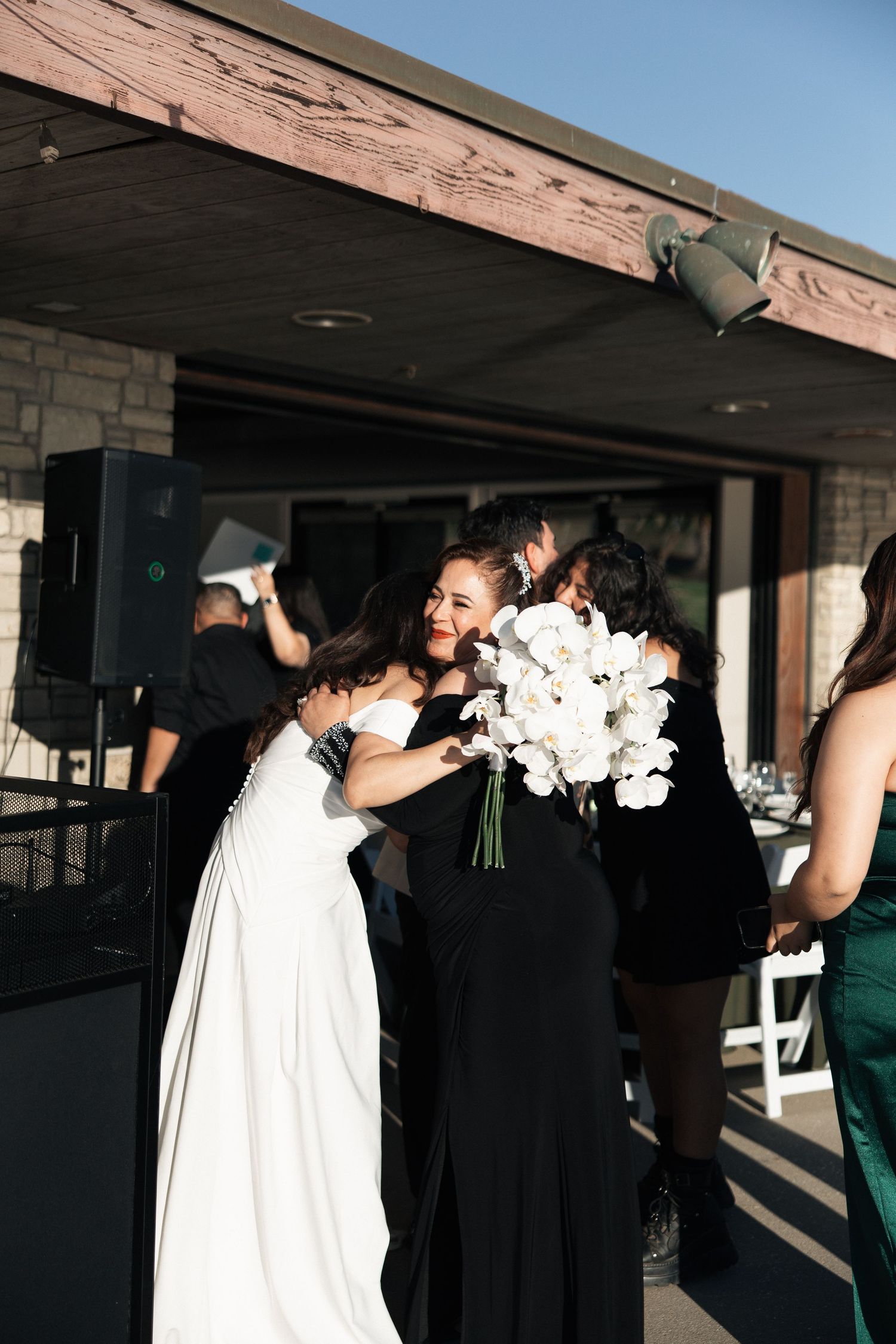 A sequence of wedding photos showing a couple in black and white attire embracing and holding bouquets under a covered patio.