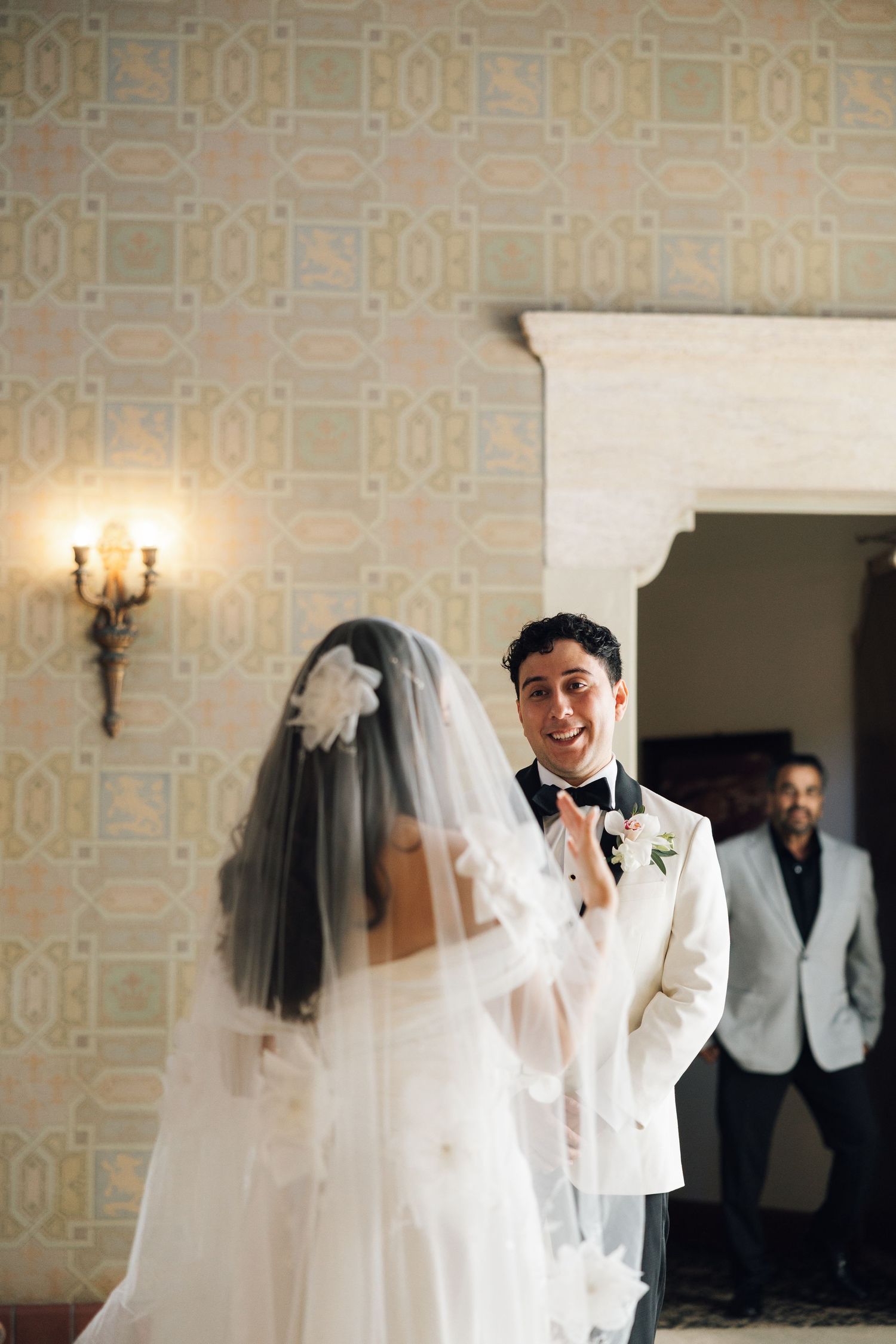 A wedding scene showing a sequence of emotional first look moments between the bride and groom in a light-filled room.
