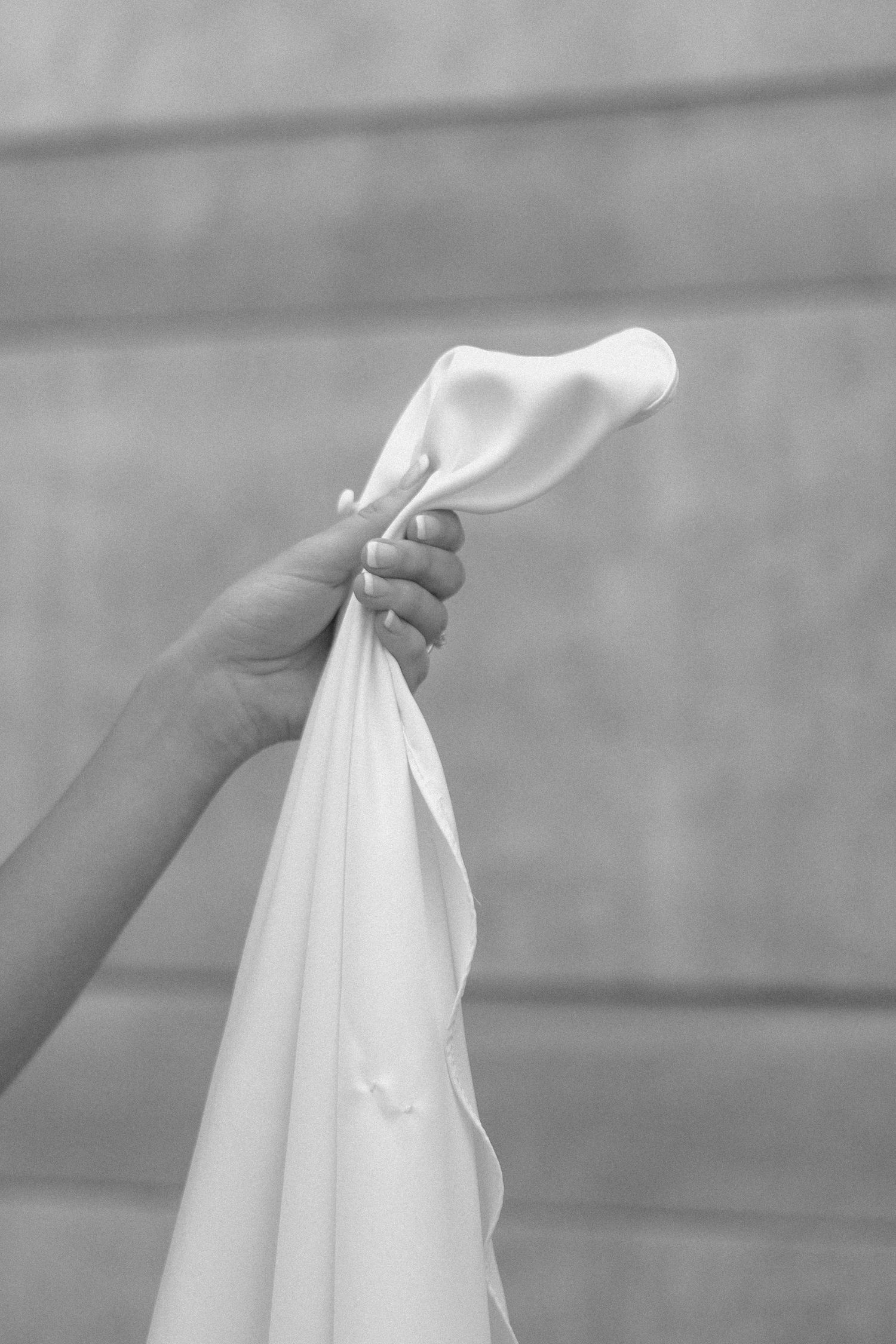Close-up black and white detail shots of delicate white fabric being held.