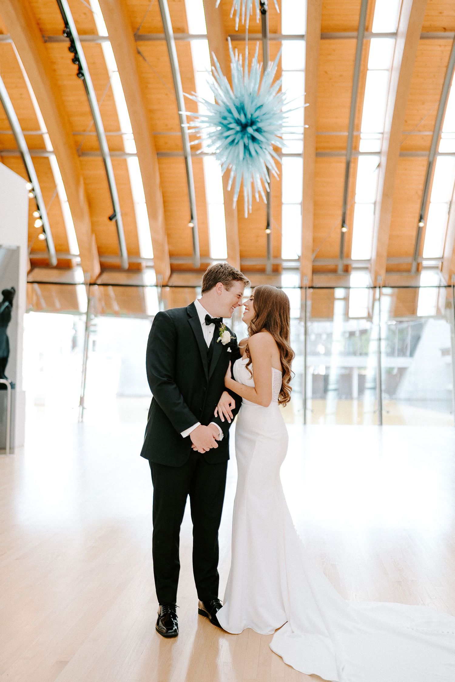 Couple dancing in elegant venue with wooden beamed ceiling and blue decorations.
