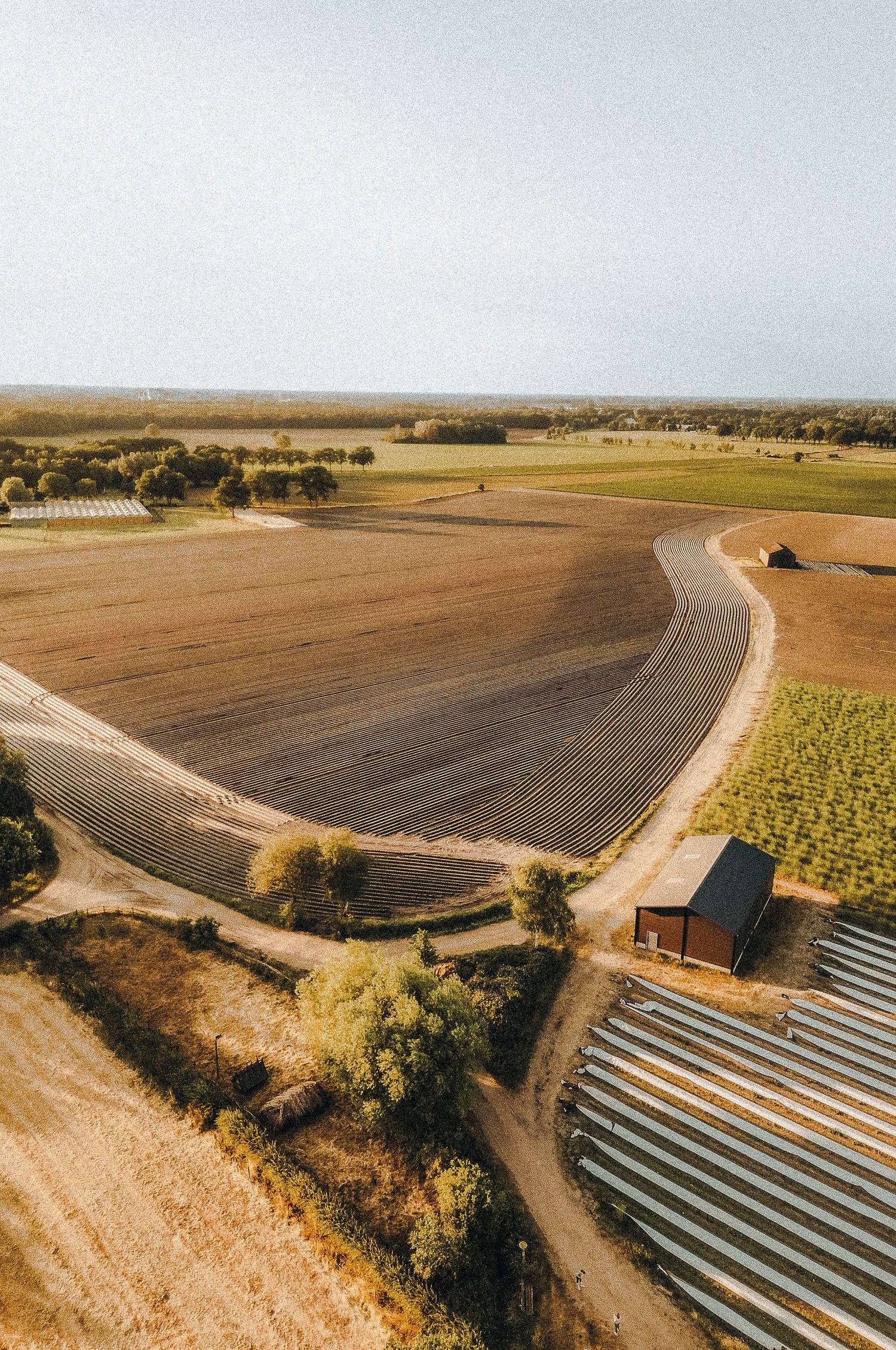 Luchtfoto van landbouwvelden met kronkelend zandpad en kleine schuur te Stiphout, Noord-Brabant. Nederland.