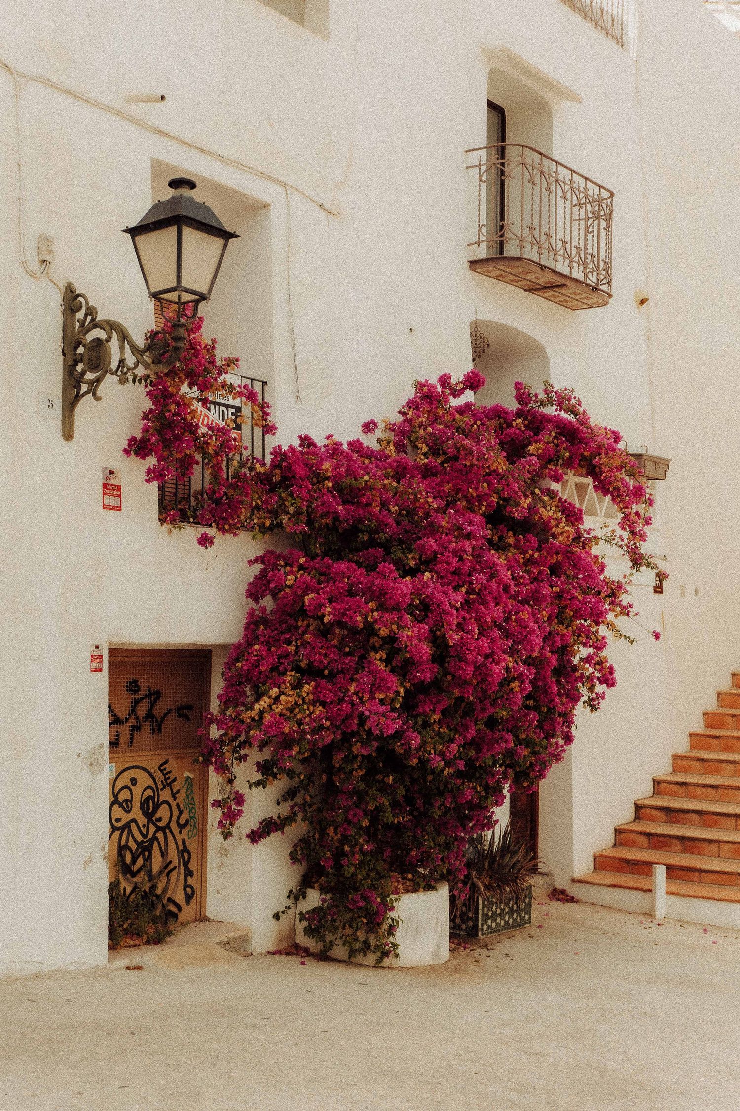 Wit huis met balkon en felroze bloeiende bougainvillea