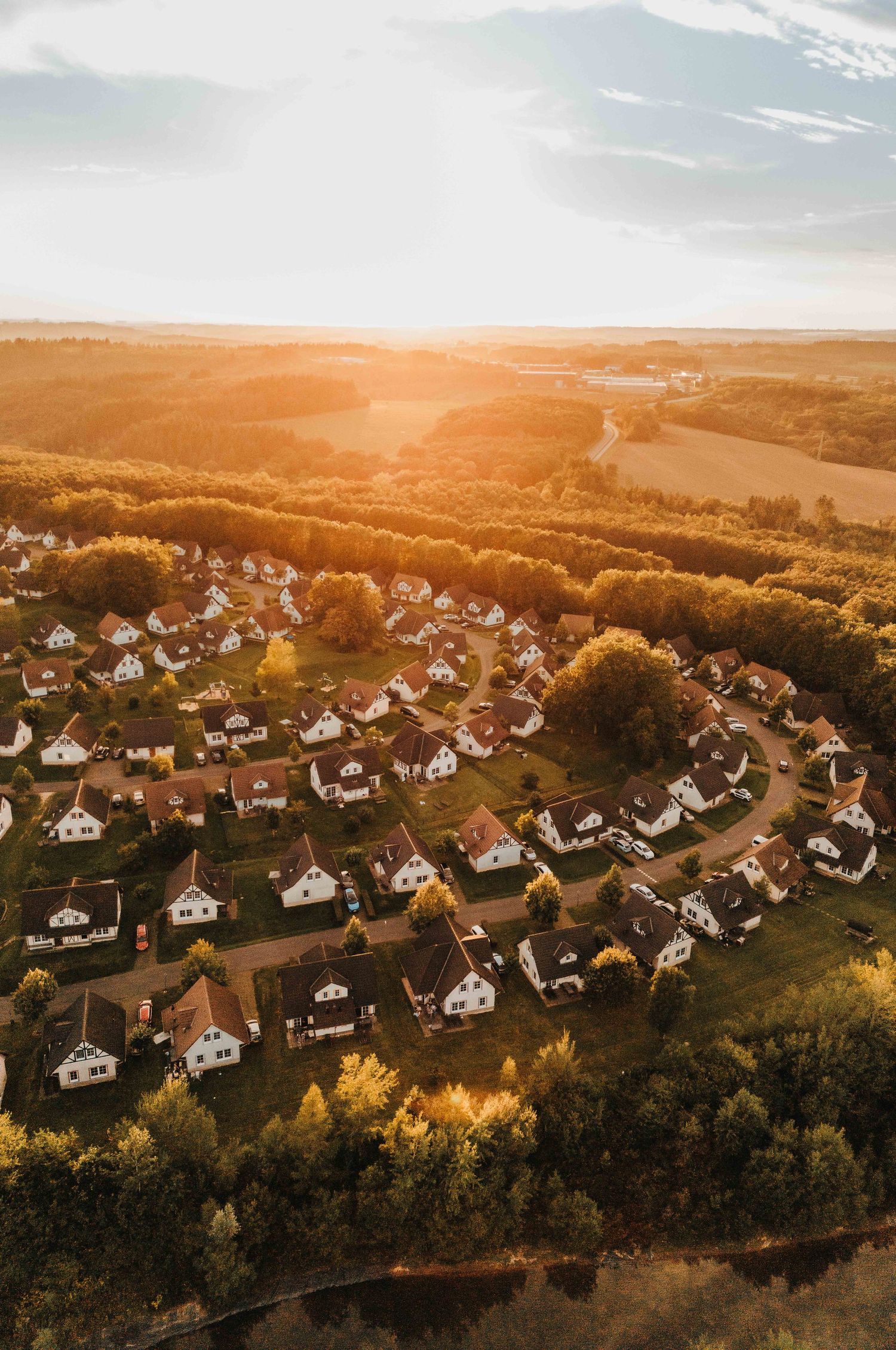 Luchtfoto van vakantiepark met huisjes tussen bomen bij ondergaande zon. Roompot park Cochem.