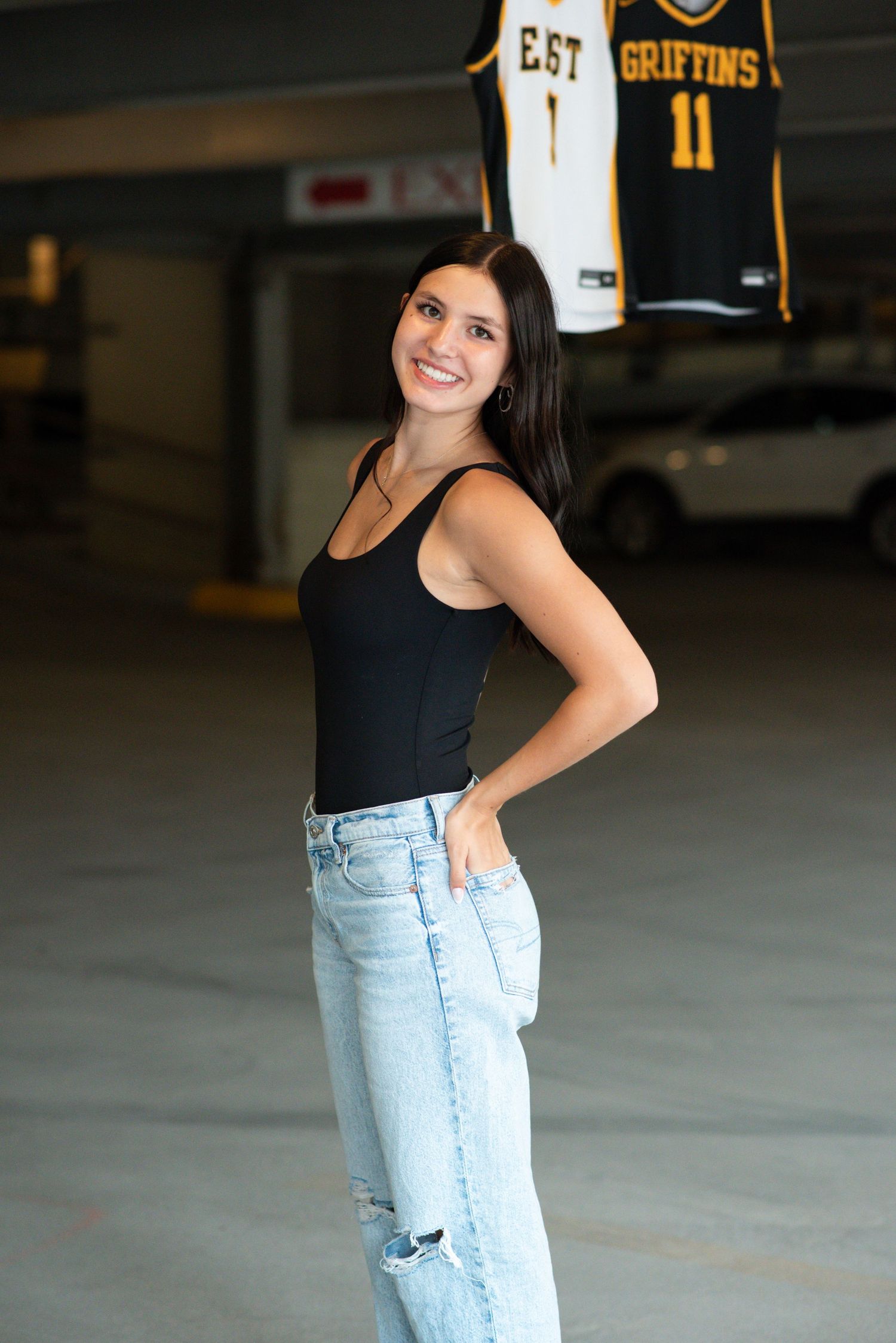 Young girl standing next to her jersey's for an outdoor photoshoot in a parking garage in Omaha, NE.