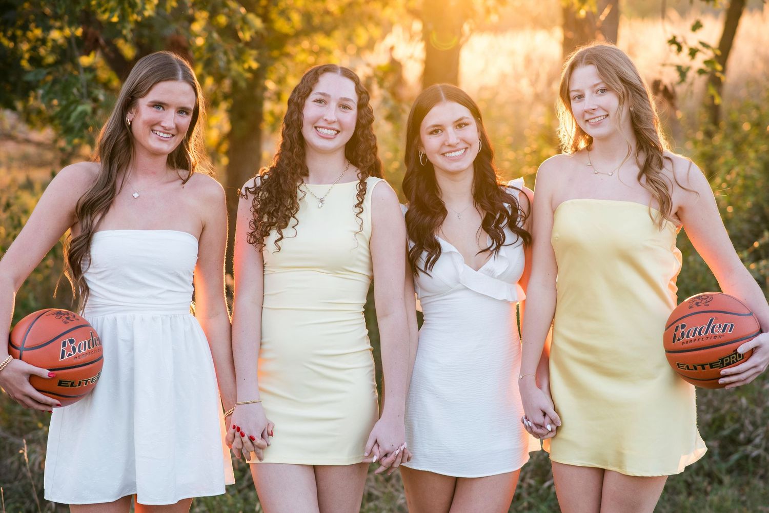 Four women holding basketball during sunset for a senior photoshoot in Gretna NE.
