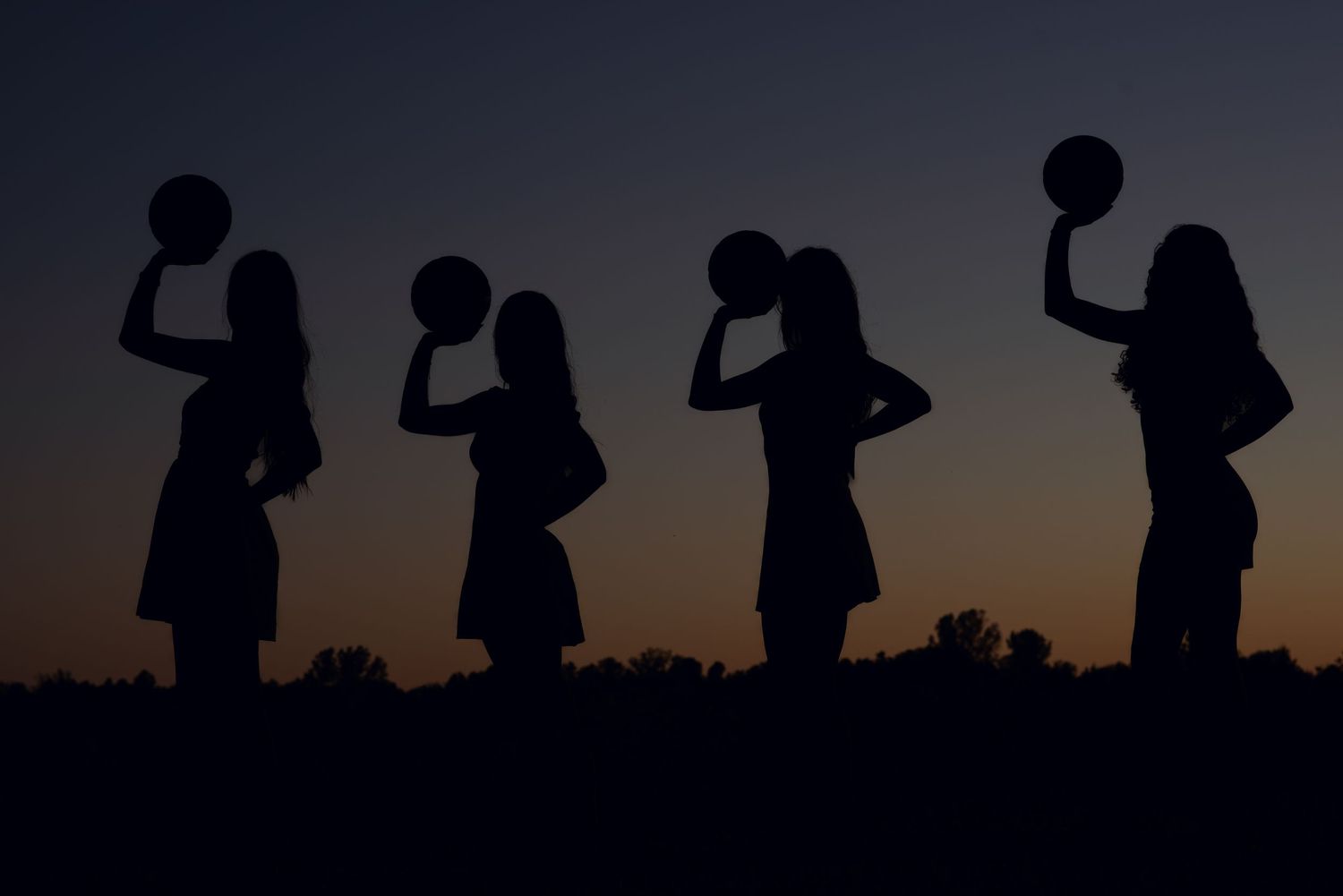 Four women holding basketballs  at night for a senior photoshoot in Gretna NE.