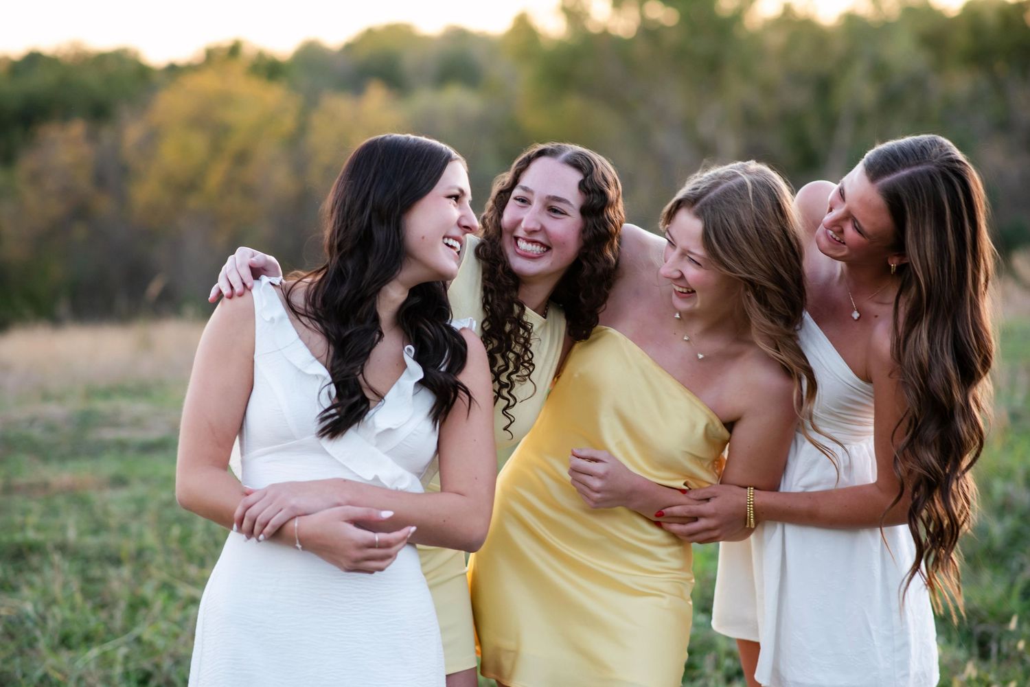 Four girls smiling and hugging during a photoshoot outdoors in Gretna NE.