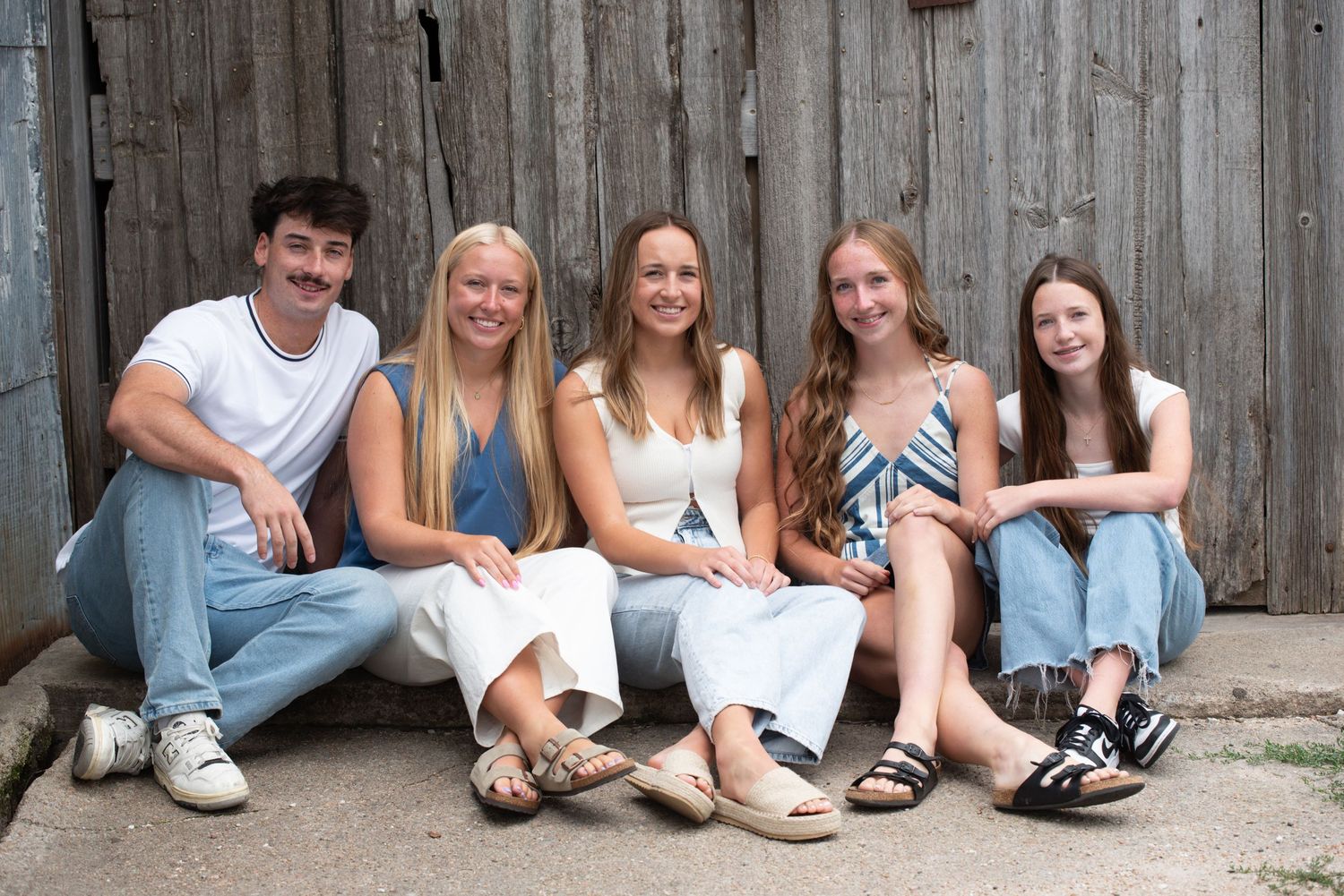 Family of five smiling and sitting together during outdoor session in Gretna, Nebraska.
