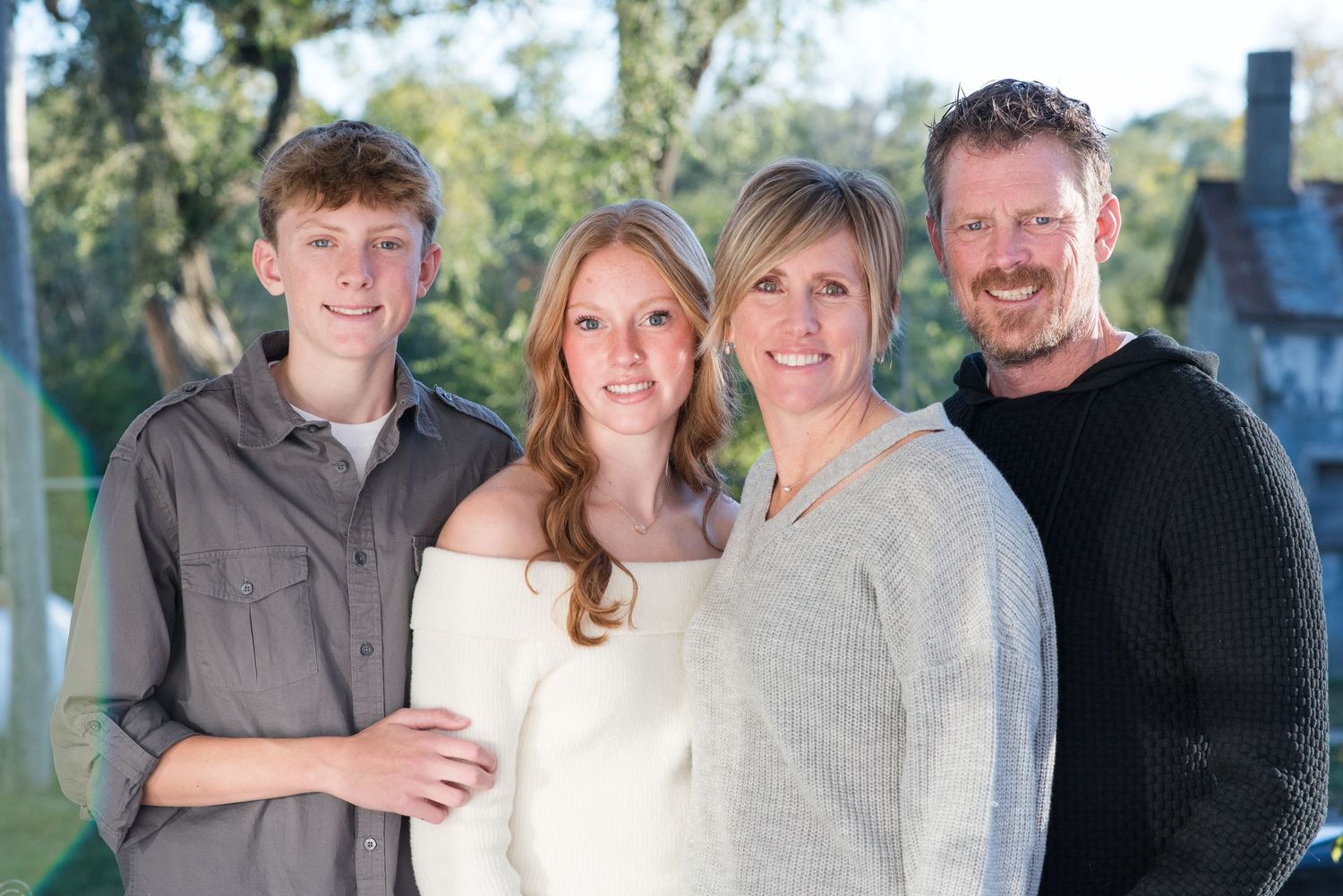 Family of four smiling and standing together during outdoor session in Gretna, Nebraska.