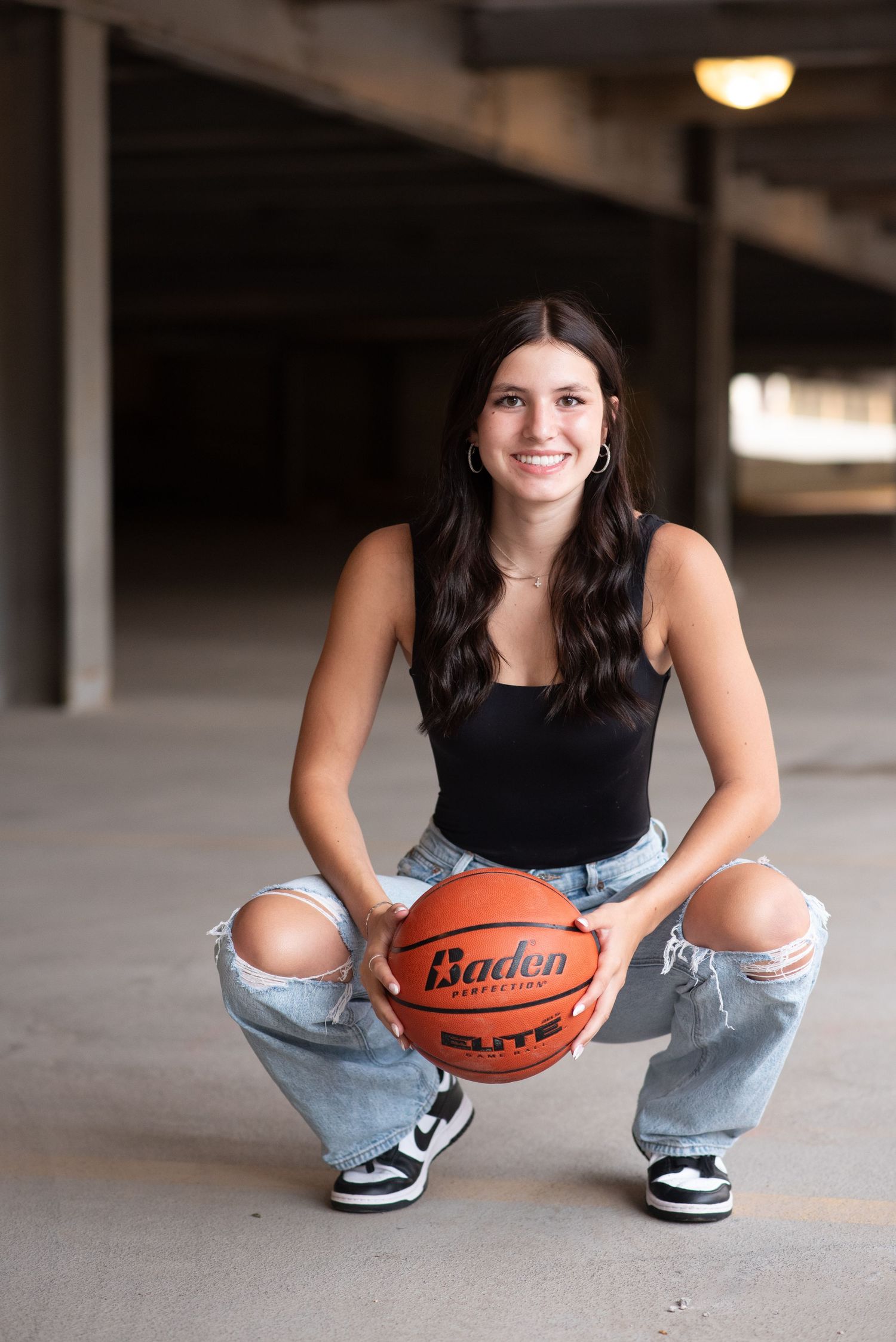 Young girl standing with a basketball for an outdoor photoshoot in a parking garage in Omaha, NE.