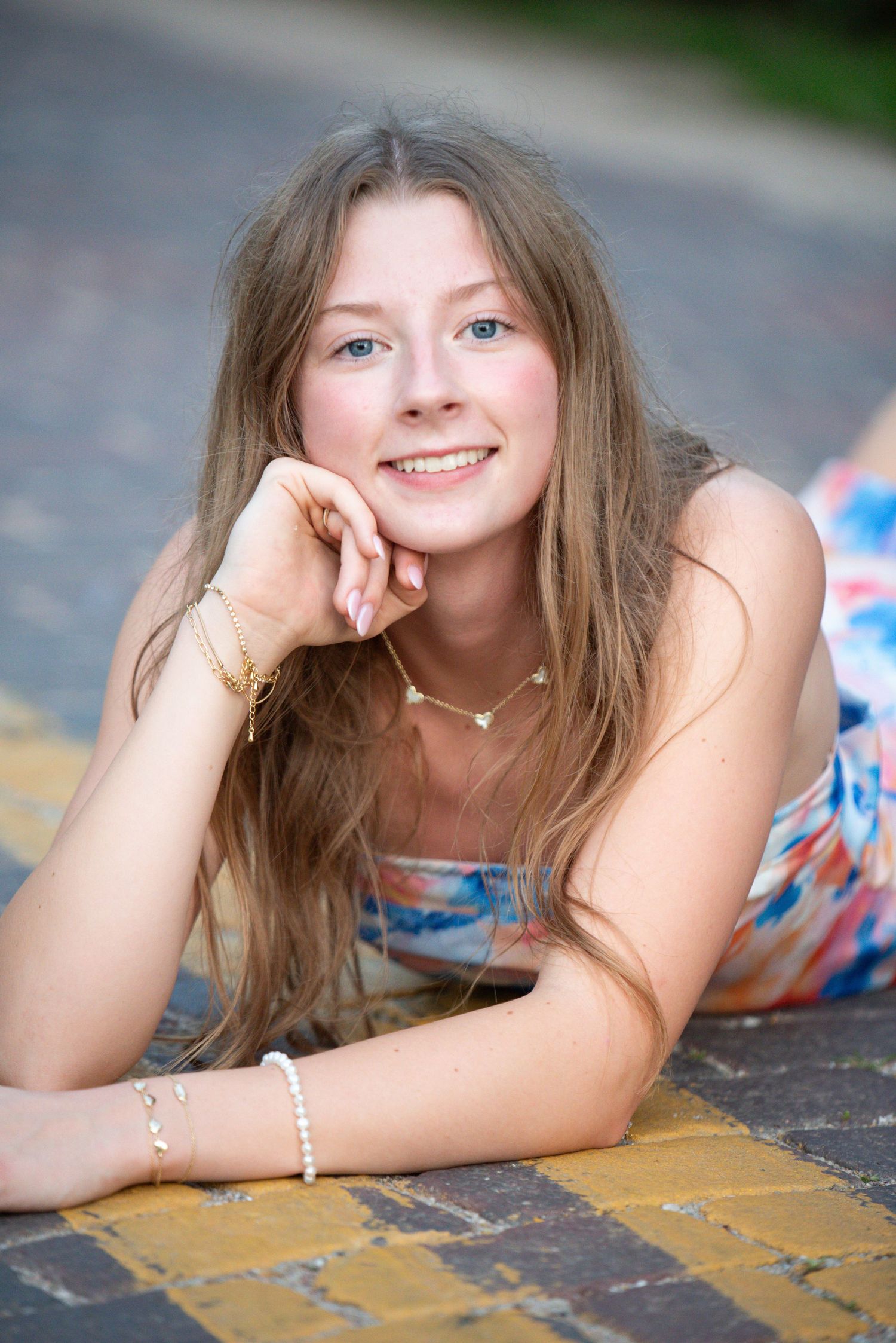Young woman laying on ground and smiling while during an outdoor photoshoot in Omaha, NE. She is on a roof top.