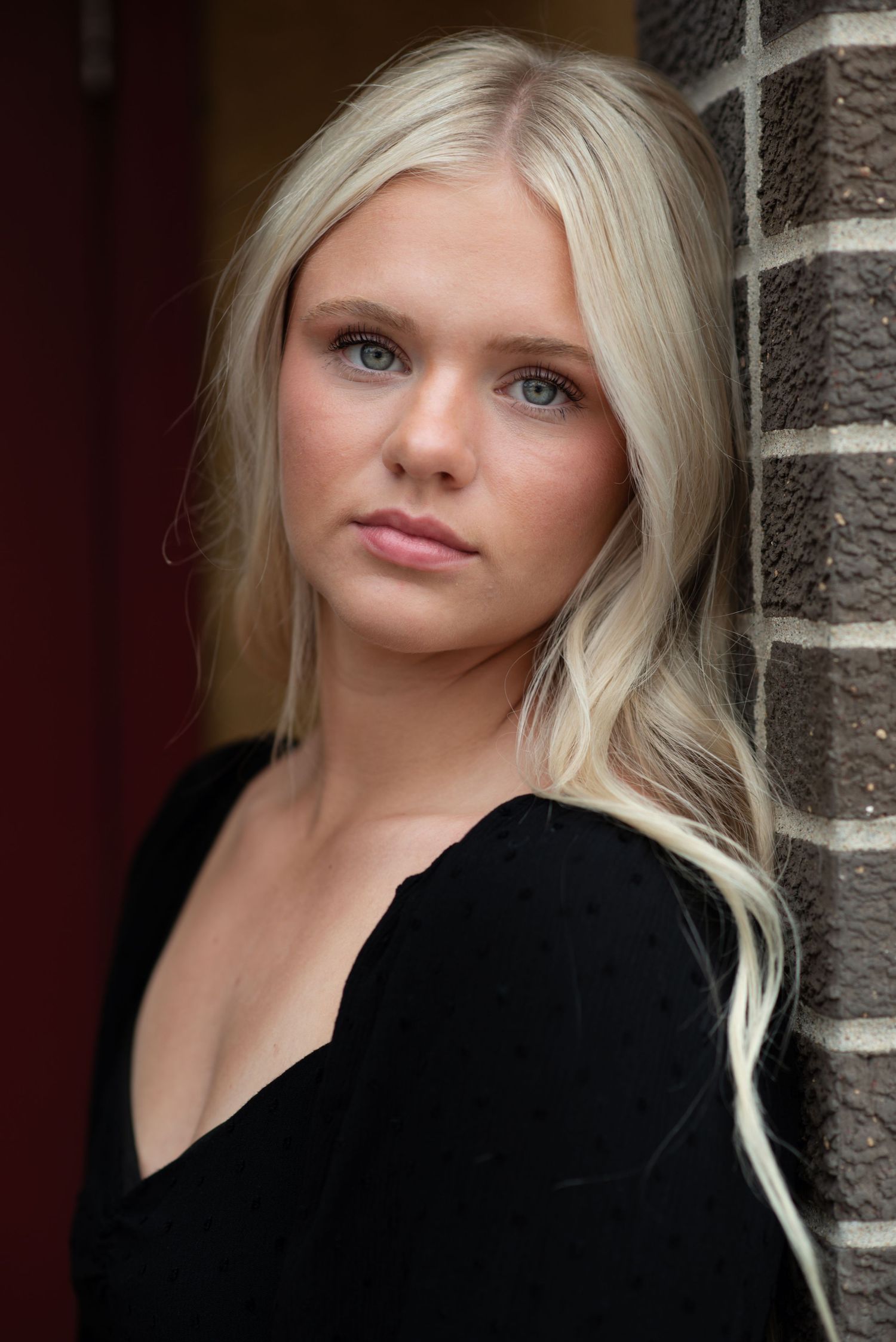 Young woman standing and smiling during an outdoor photoshoot in Omaha, NE.