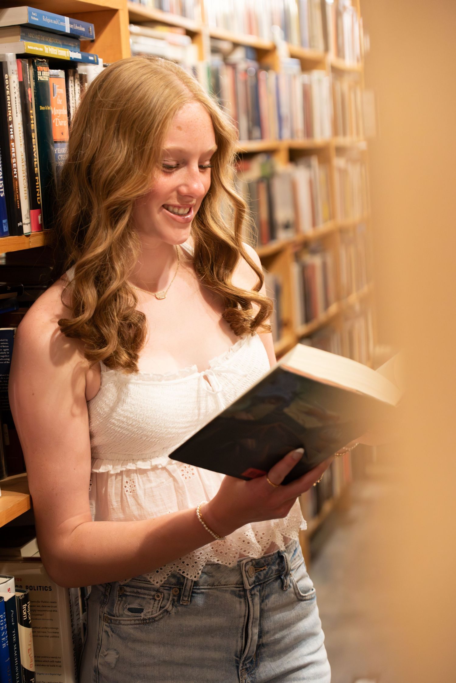Young woman standing and smiling an indoor photoshoot  at a library in Omaha, NE. She is on a roof top.