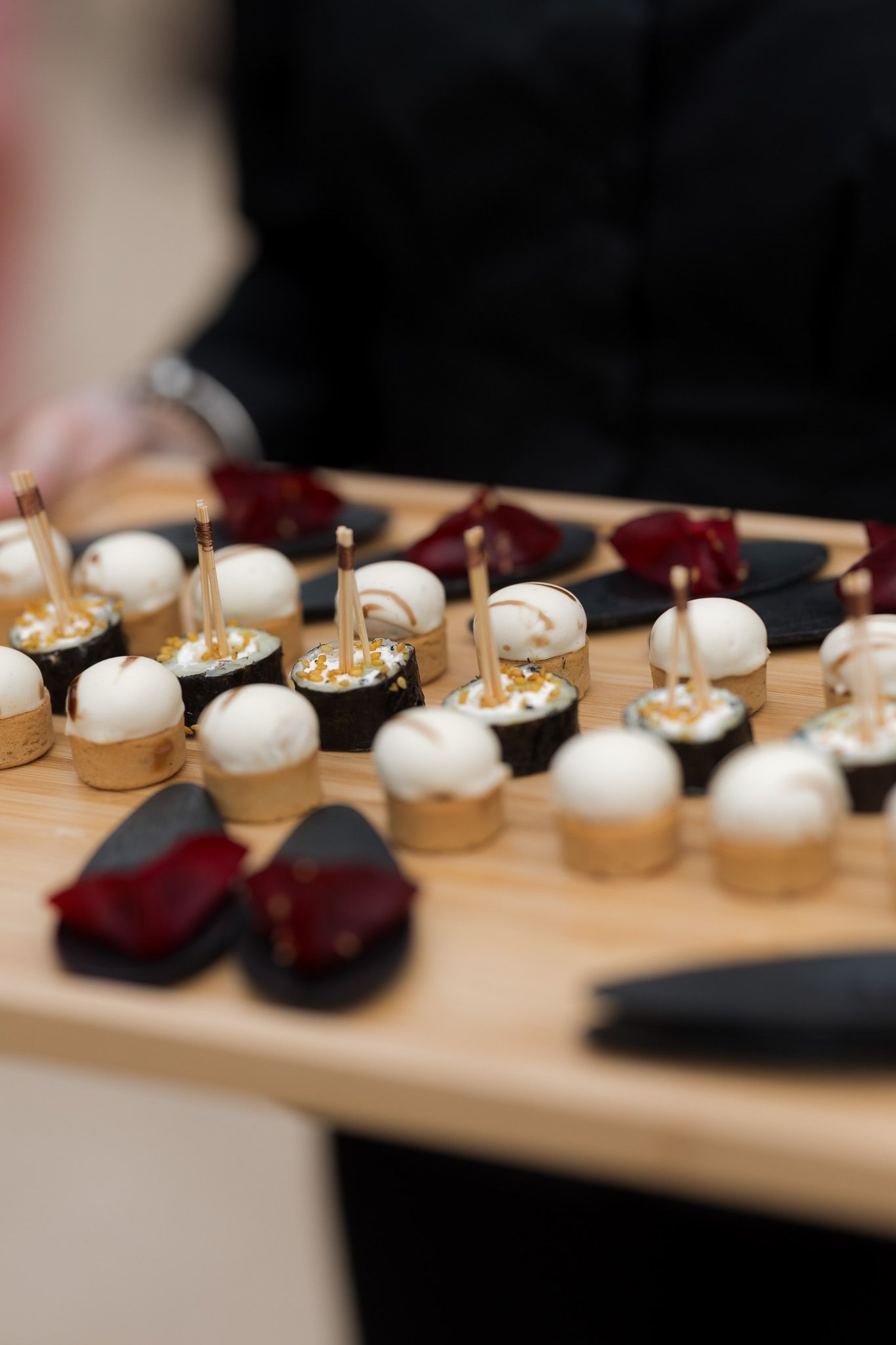 Elegant appetizer tray with white chocolate truffles, gold-topped canapes, and dark chocolate desserts served at a catered event.