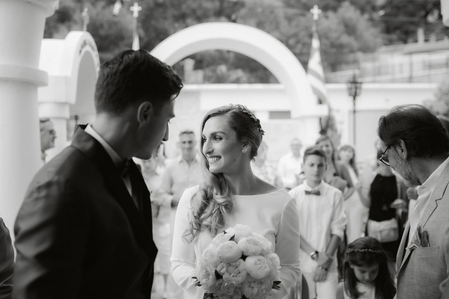 Black and white wedding photo showing guests celebrating and dancing at an elegant reception venue.