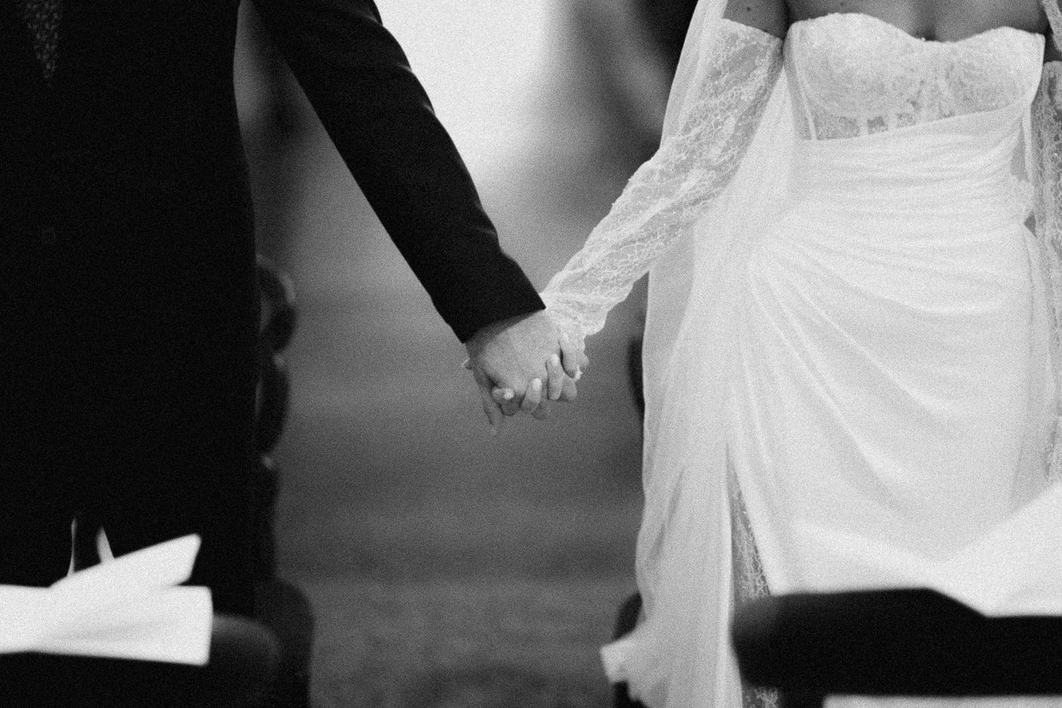 Monochrome wedding photo showing a couple dancing in formal attire with the bride in a flowing white dress.