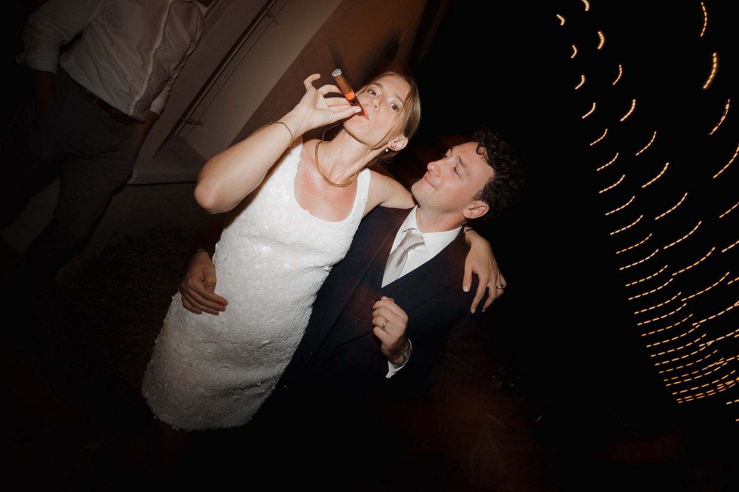 Couple dancing together at a wedding reception with string lights decorating the dark venue ceiling.