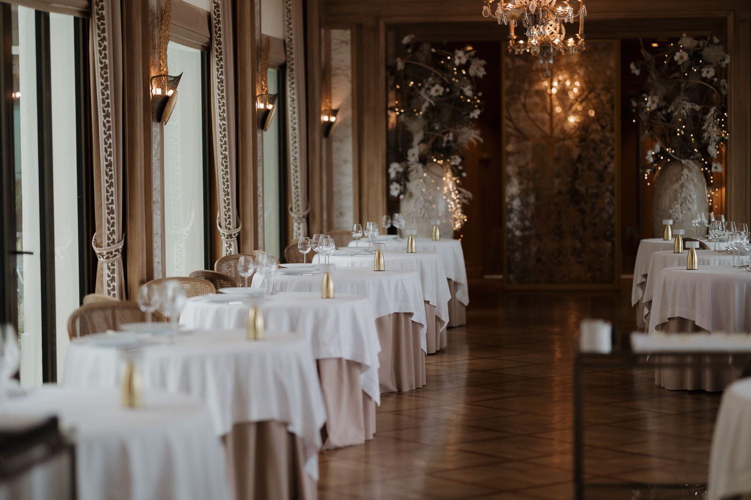Elegant wedding reception venue with white tablecloths, ornate chandeliers and classic architectural details.