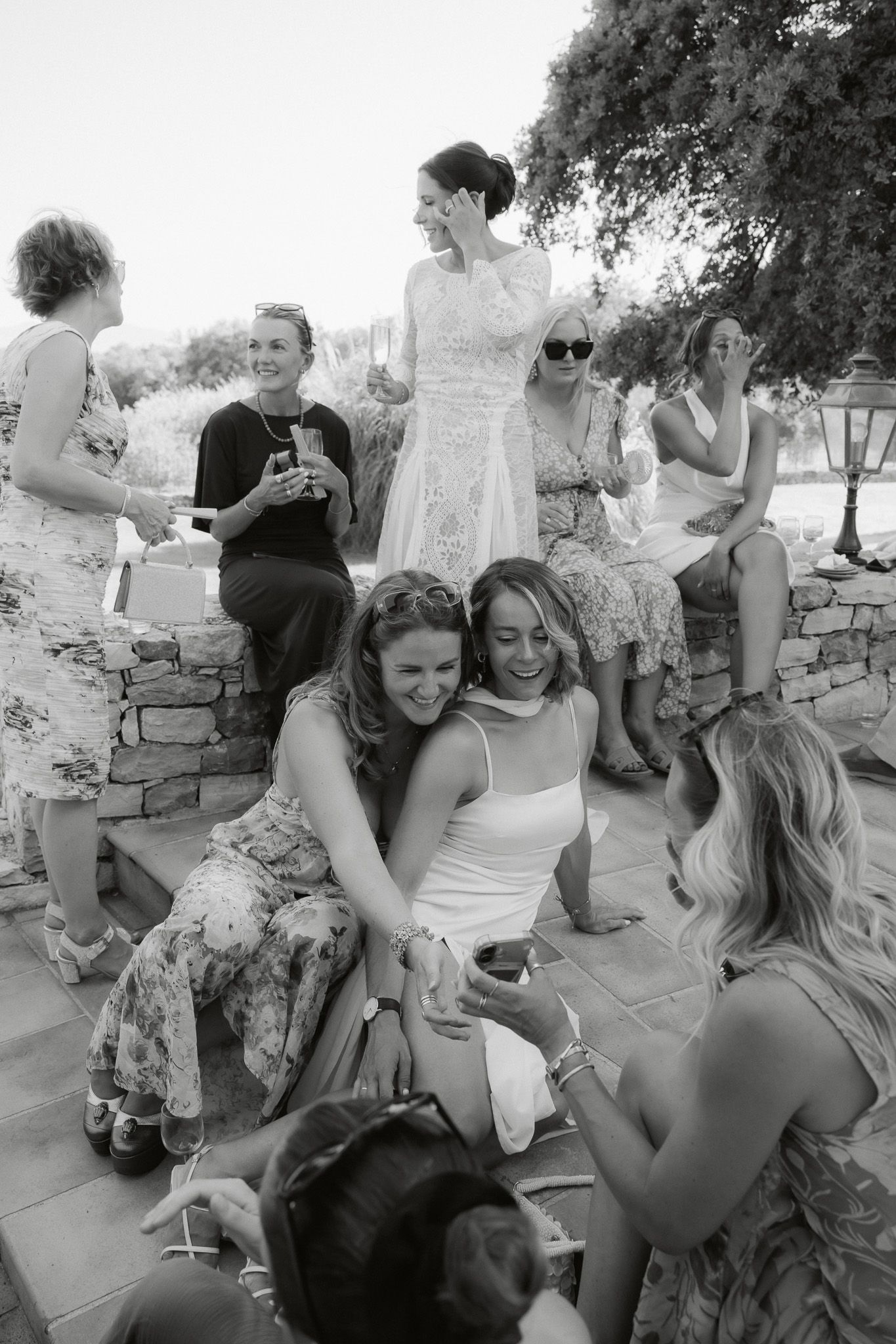Wedding guests celebrate and laugh together outdoors in black and white photo at a summer wedding.