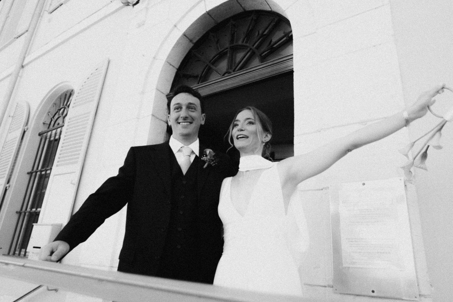 Black and white photo of guests enjoying a formal event under an elegant white architectural structure.