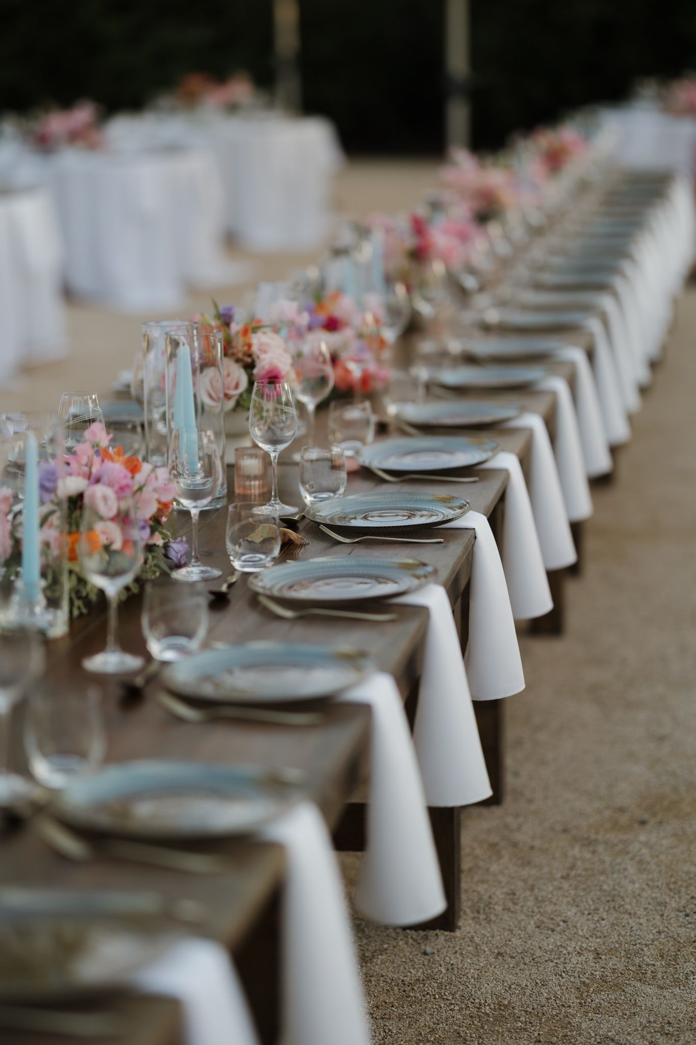 Elegant wedding reception table setting with white linens, place settings and delicate pink floral centerpieces.