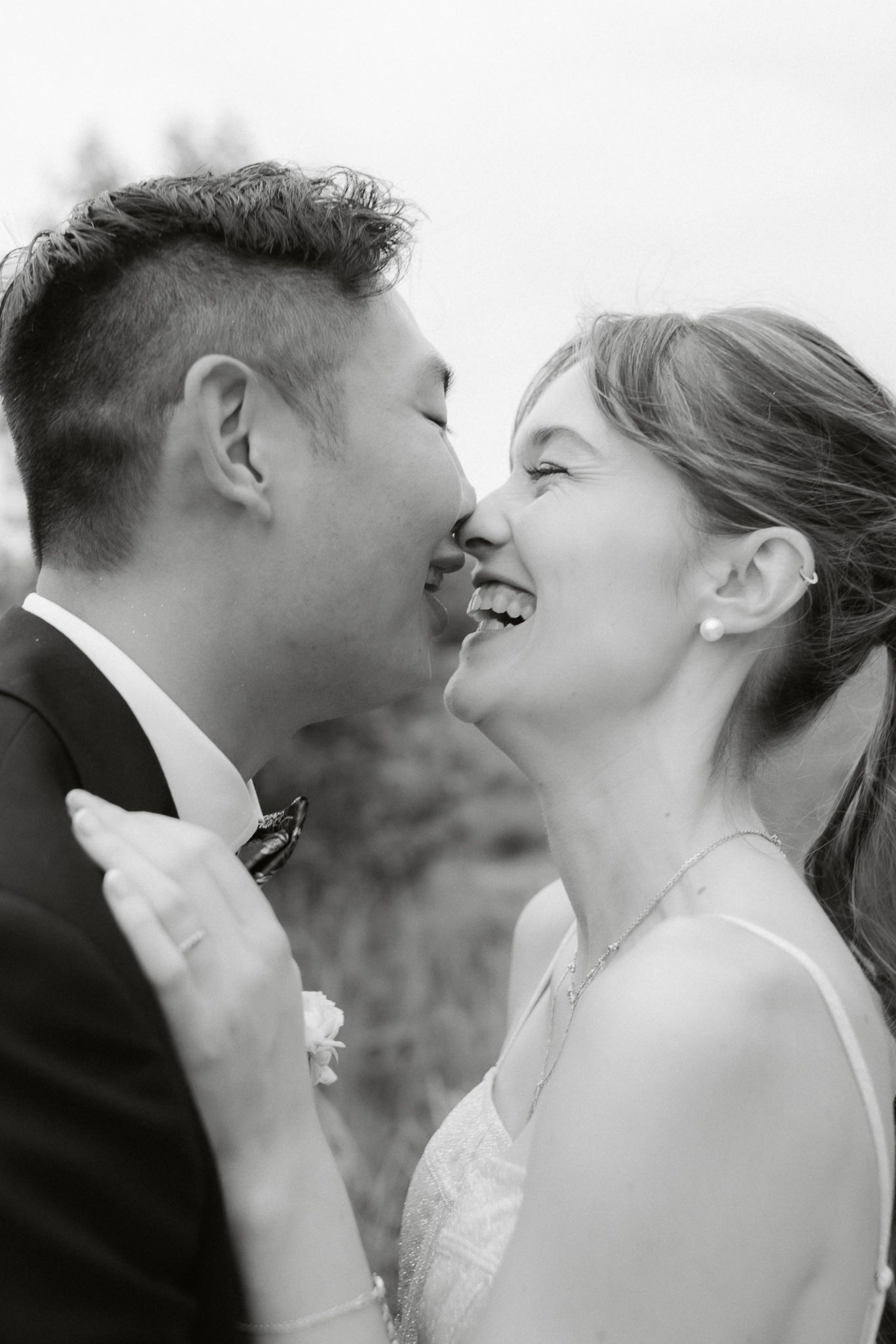 A joyful black and white wedding photo showing an intimate moment between a couple sharing laughter and closeness.