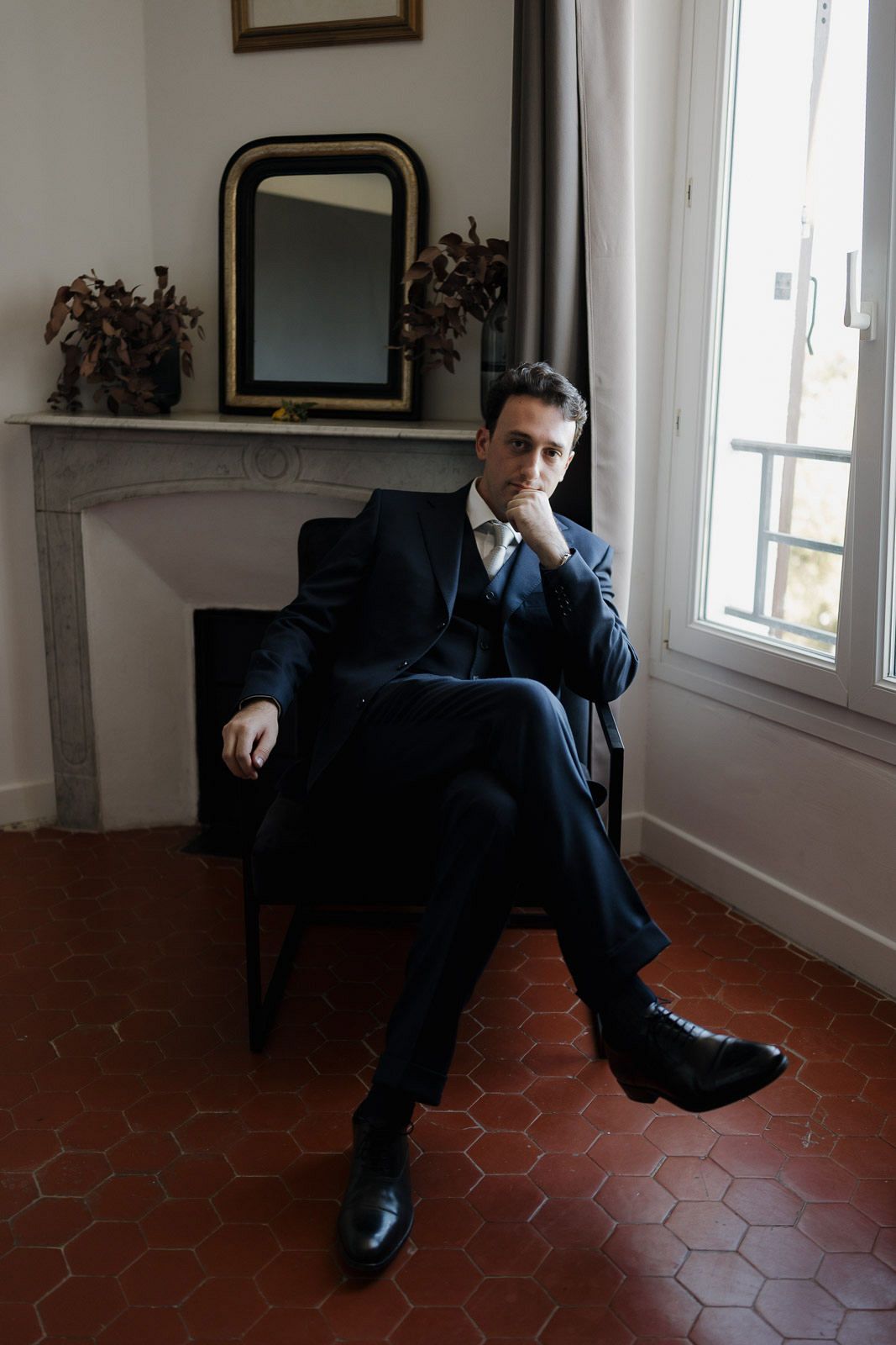 A series of artistic black and white photographs showing a person in a suit lounging on hexagonal tile floors.