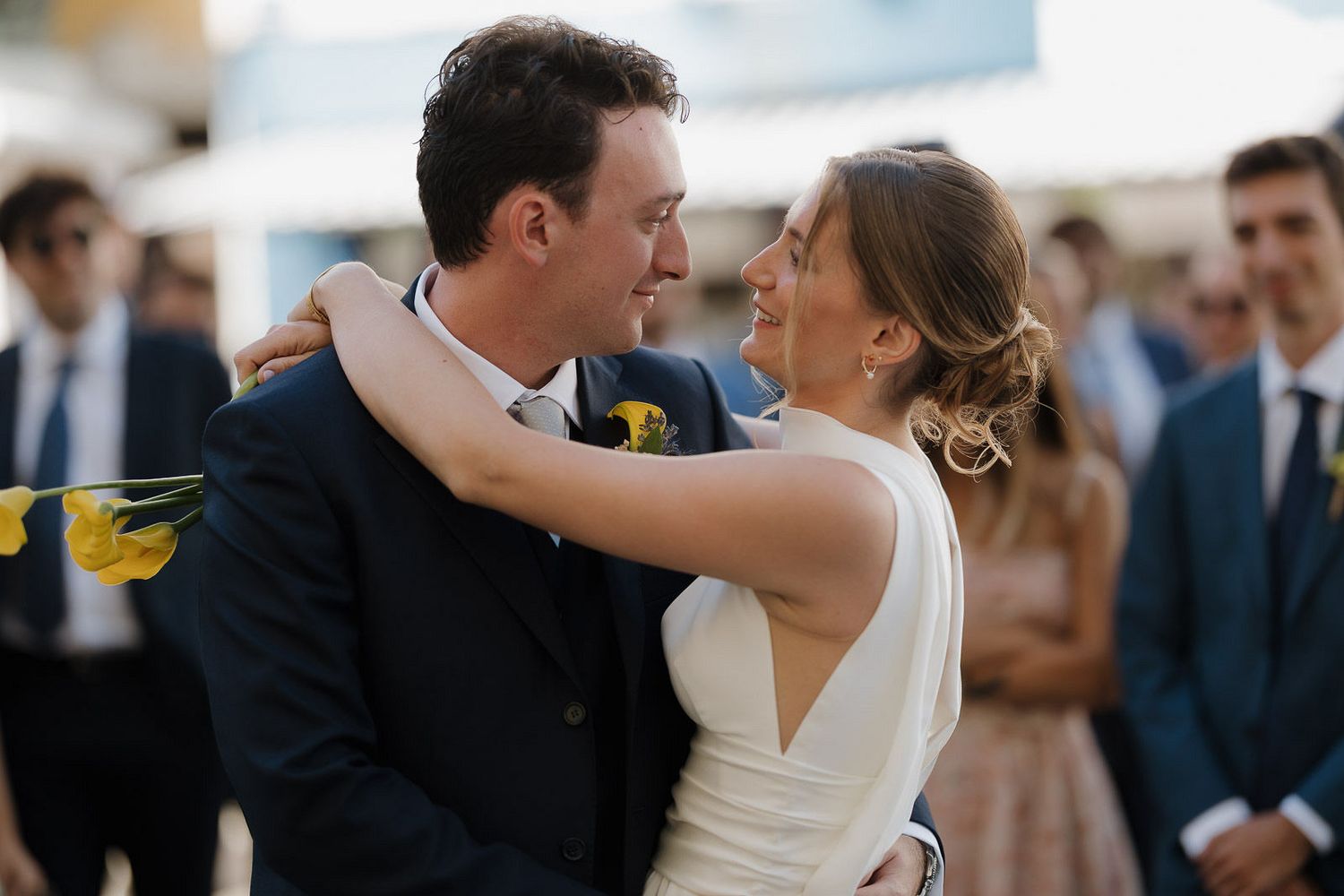 A couple shares a romantic dance at their wedding celebration while guests look on in the background.
